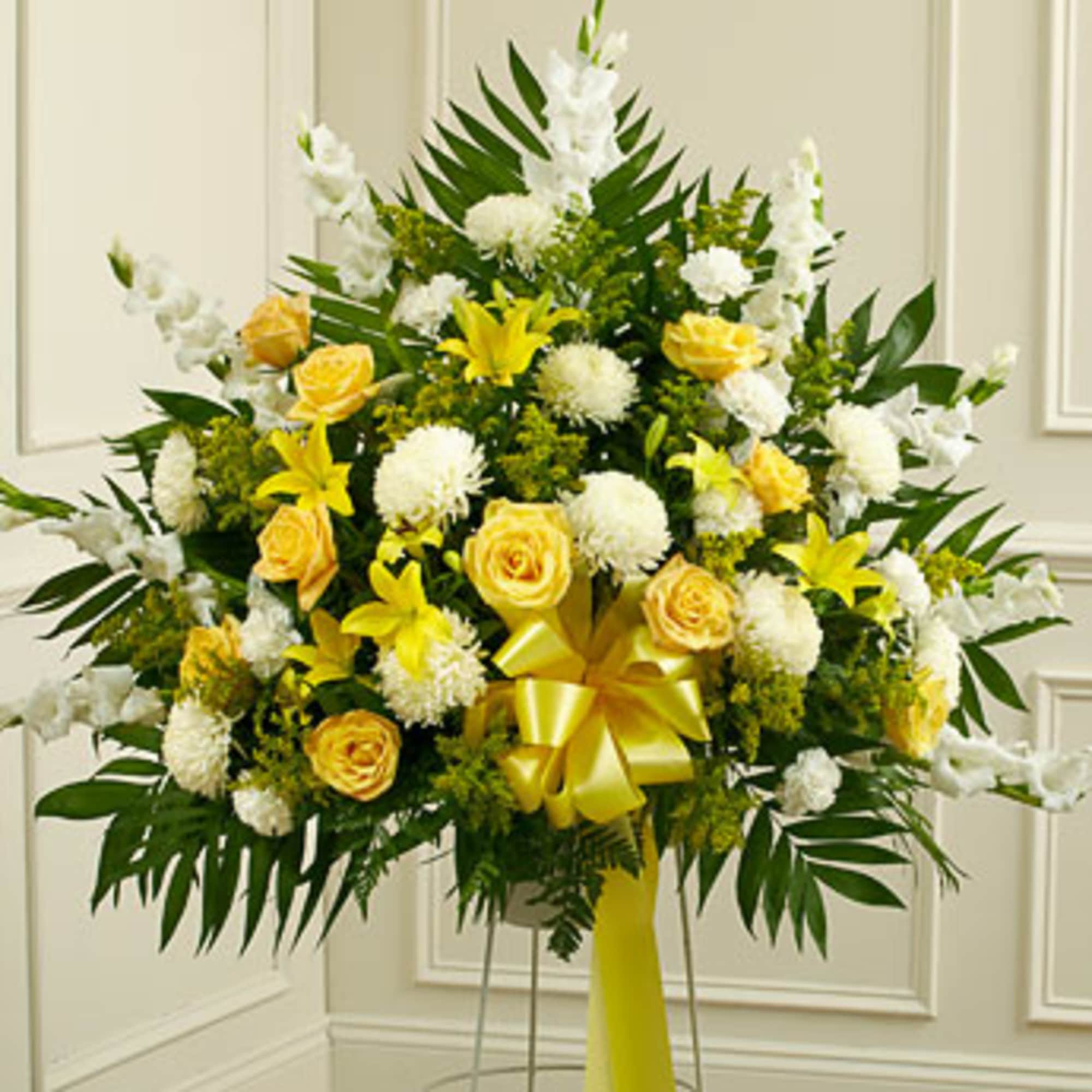 Yellow roses and white flowers in a standing arrangement with a yellow ribbon