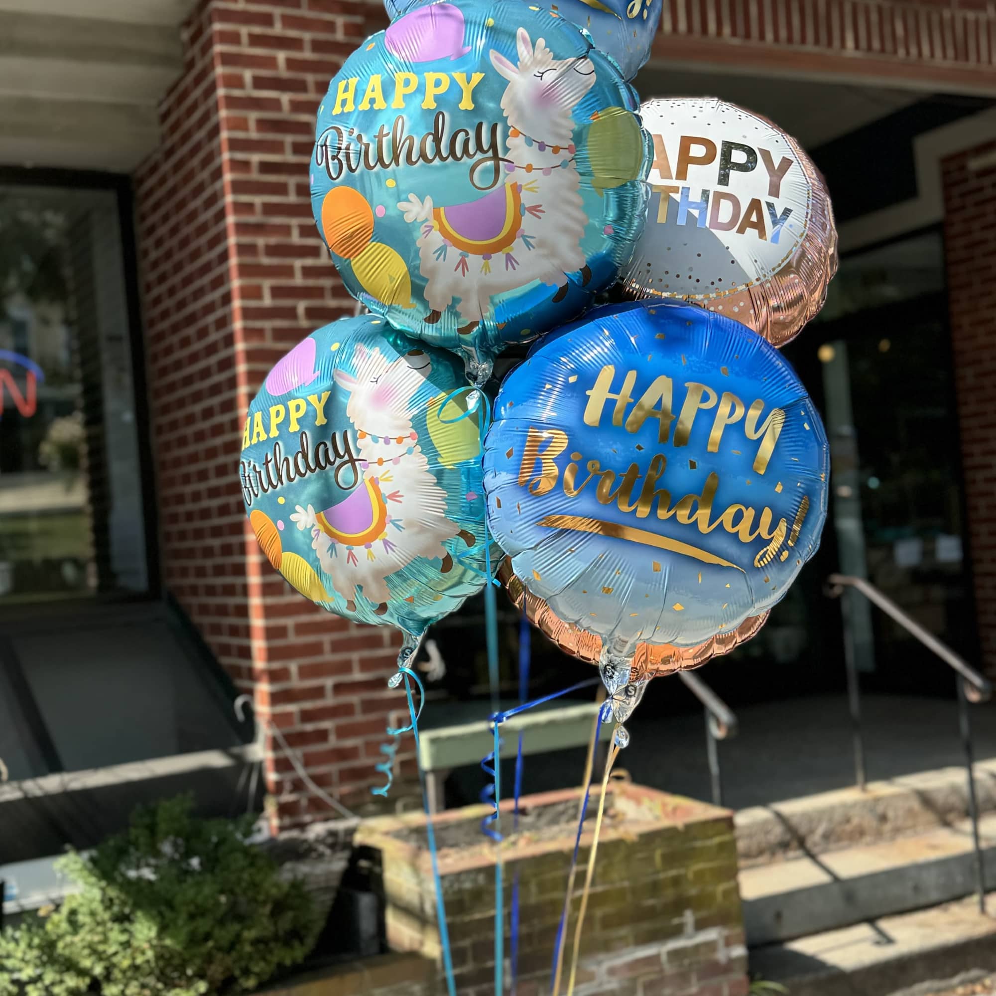 Cluster of birthday balloons with llama graphics and gold lettering