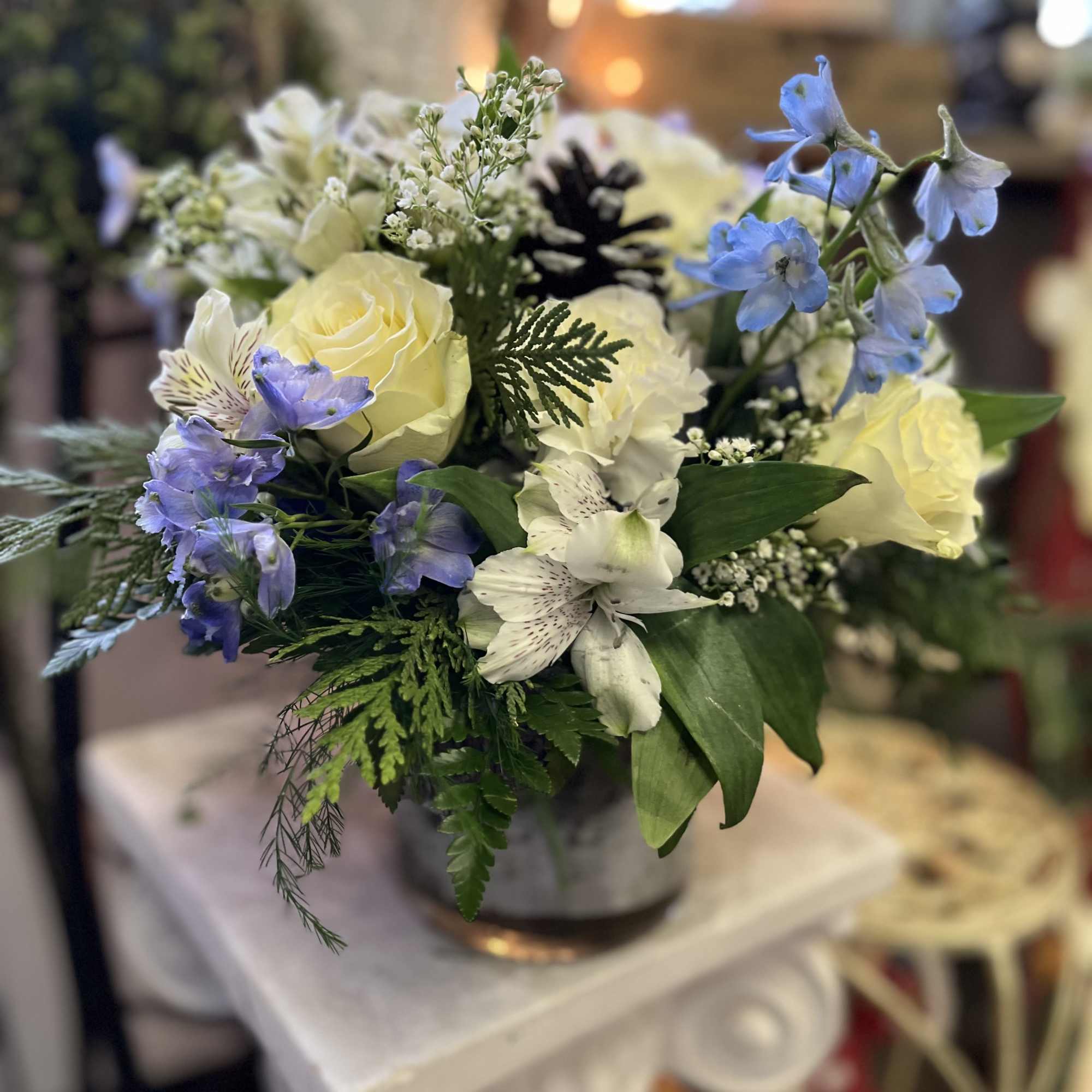 Bouquet of pale yellow roses and blue flowers in a vase