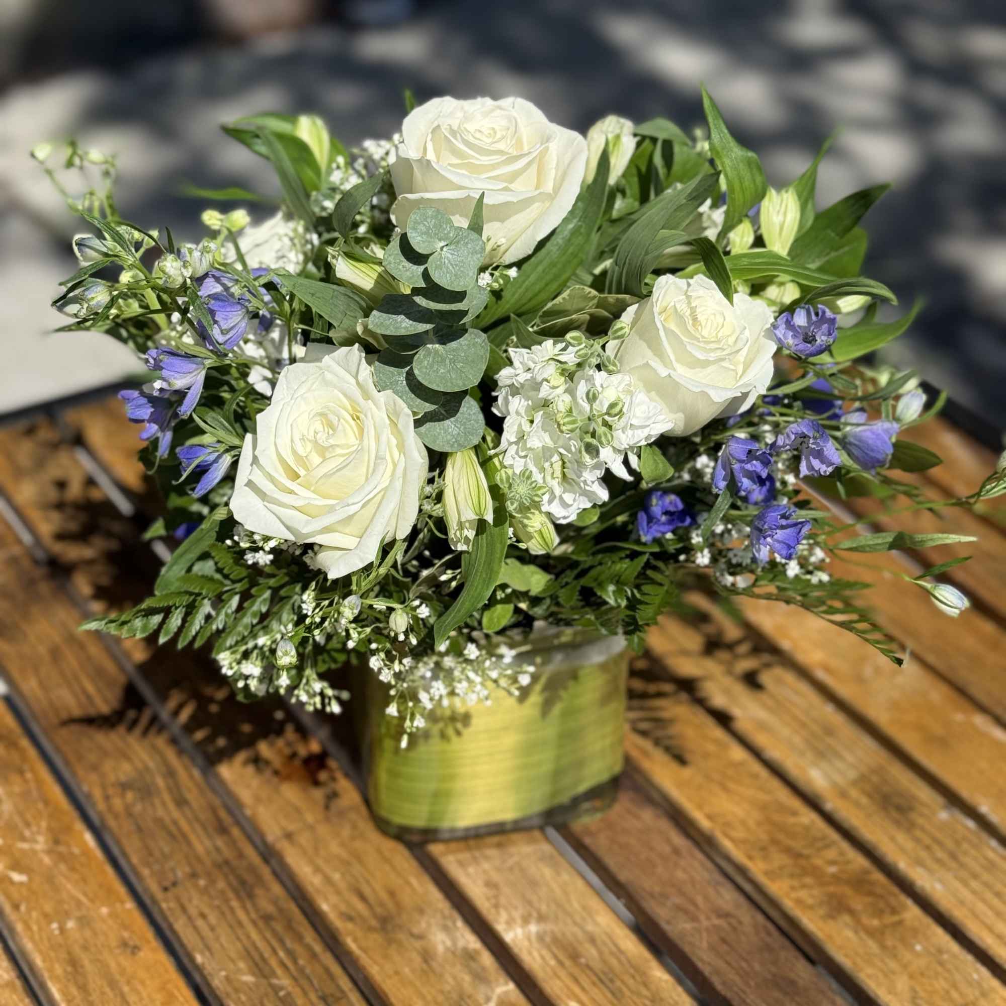 White roses and purple flowers in a square glass vase