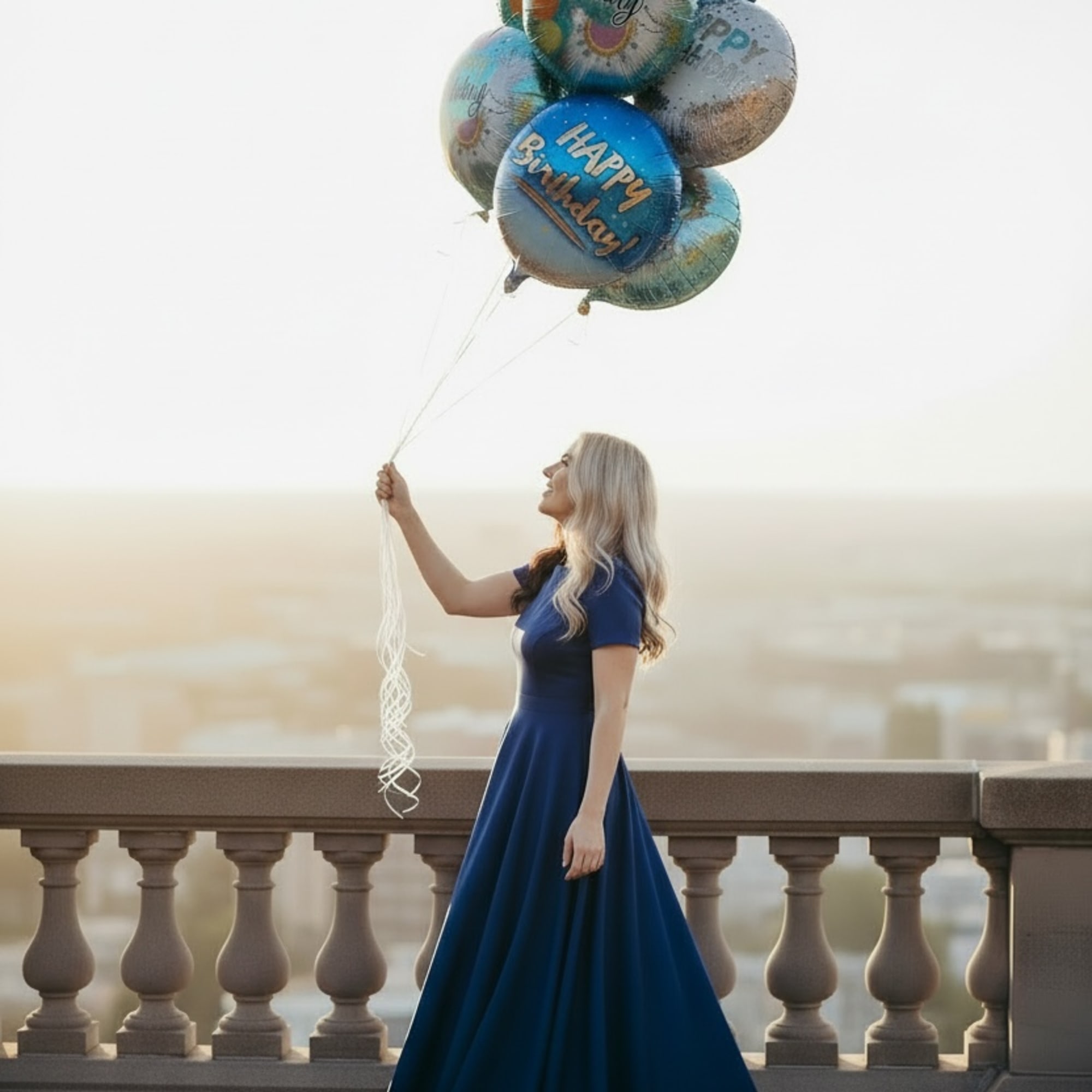 Woman in a blue dress holding a cluster of birthday balloons