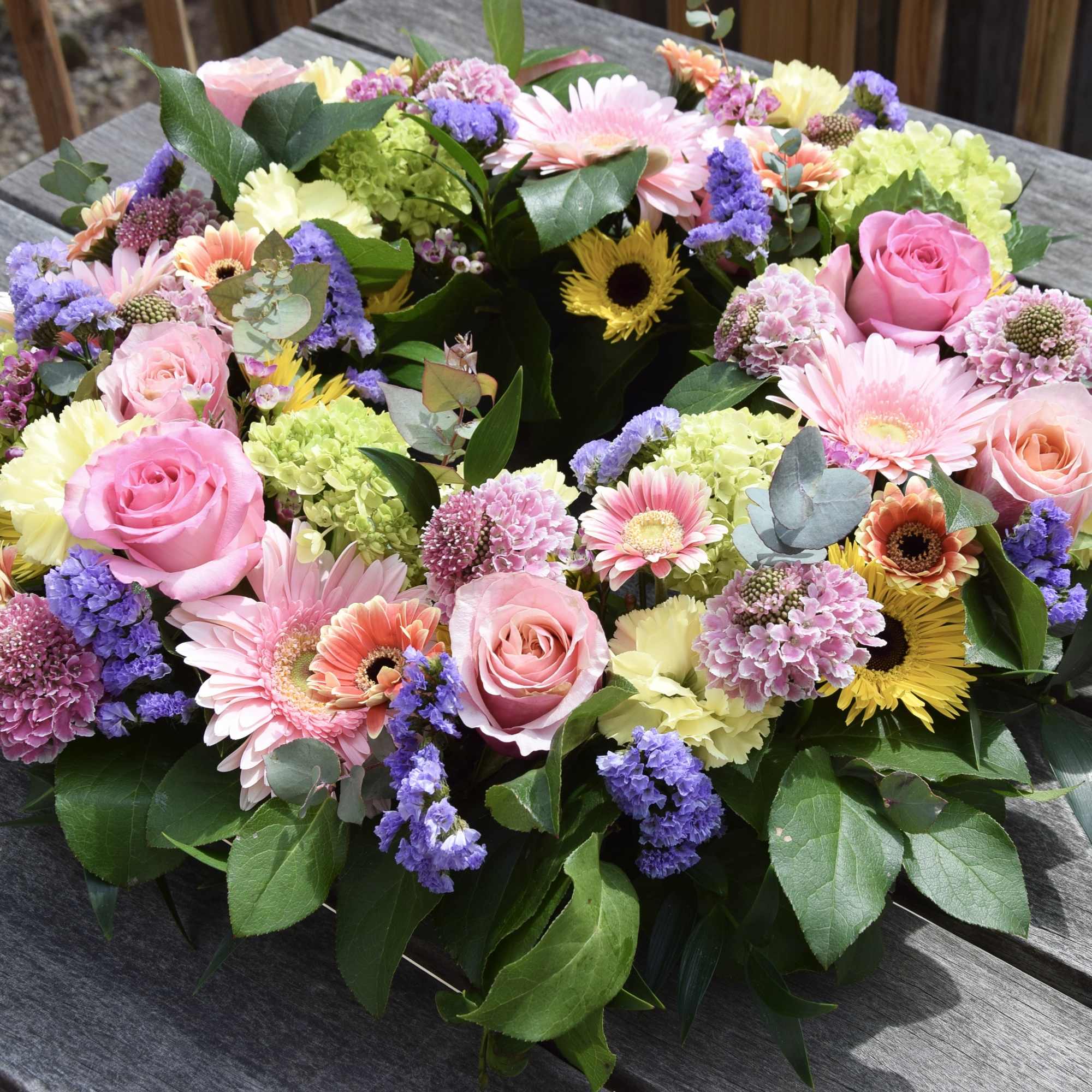 Circular bouquet of pink roses and mixed pastel flowers on a table
