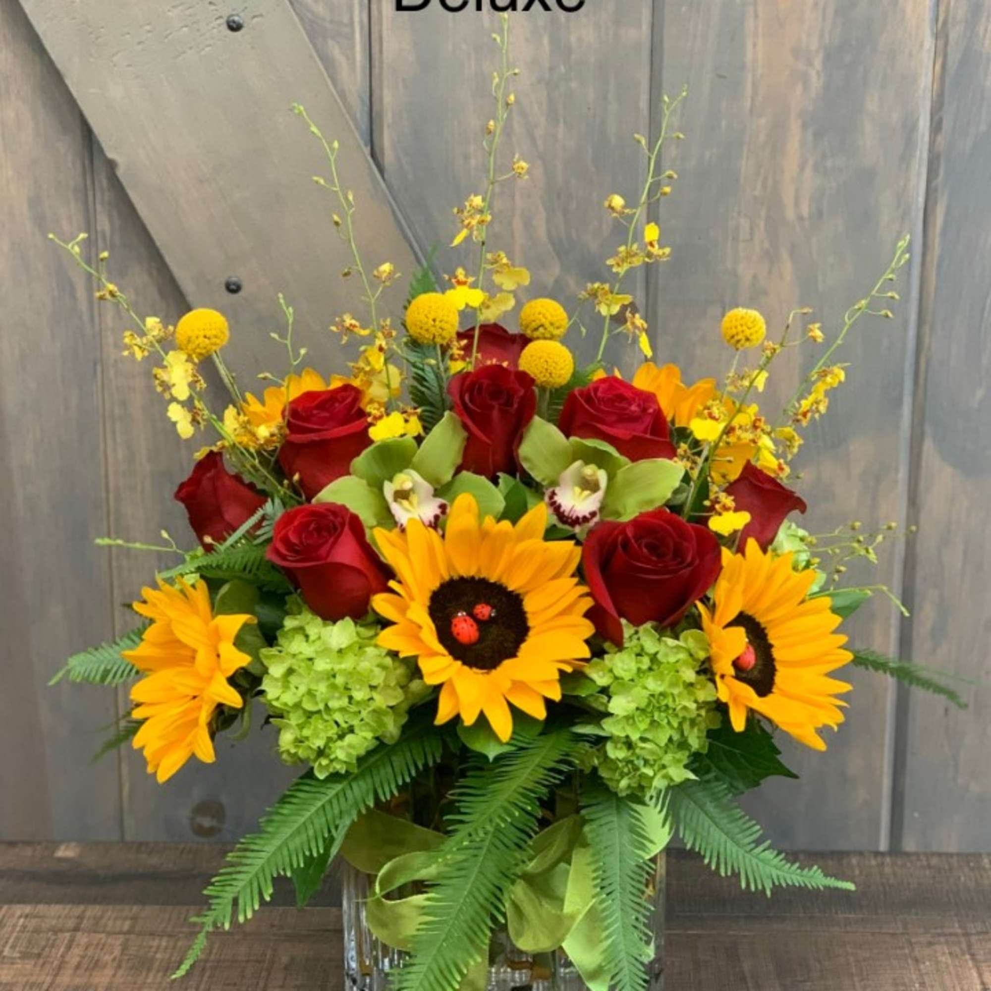 Bouquet of red roses and sunflowers in a glass vase
