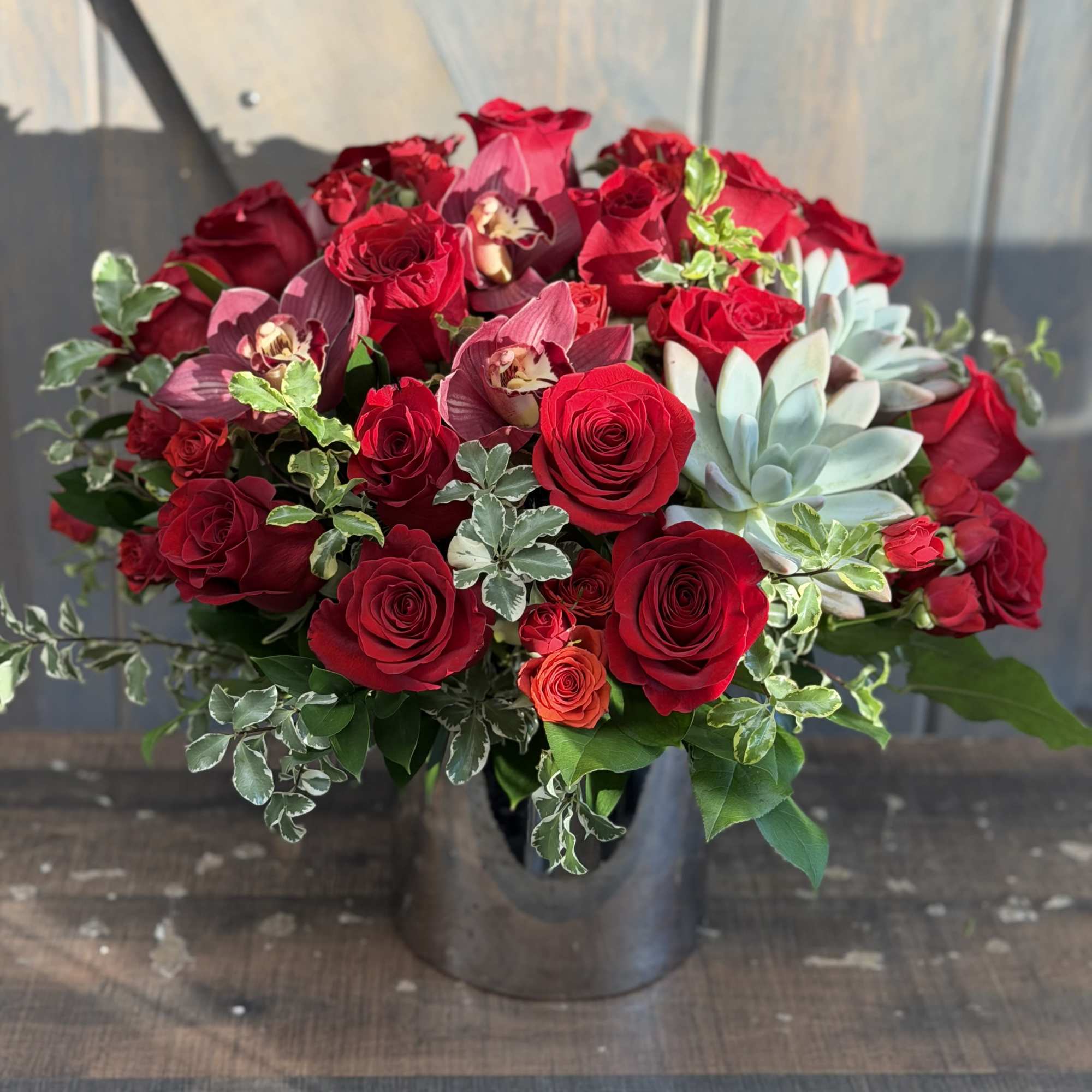 Red roses and succulents arranged in a black vase