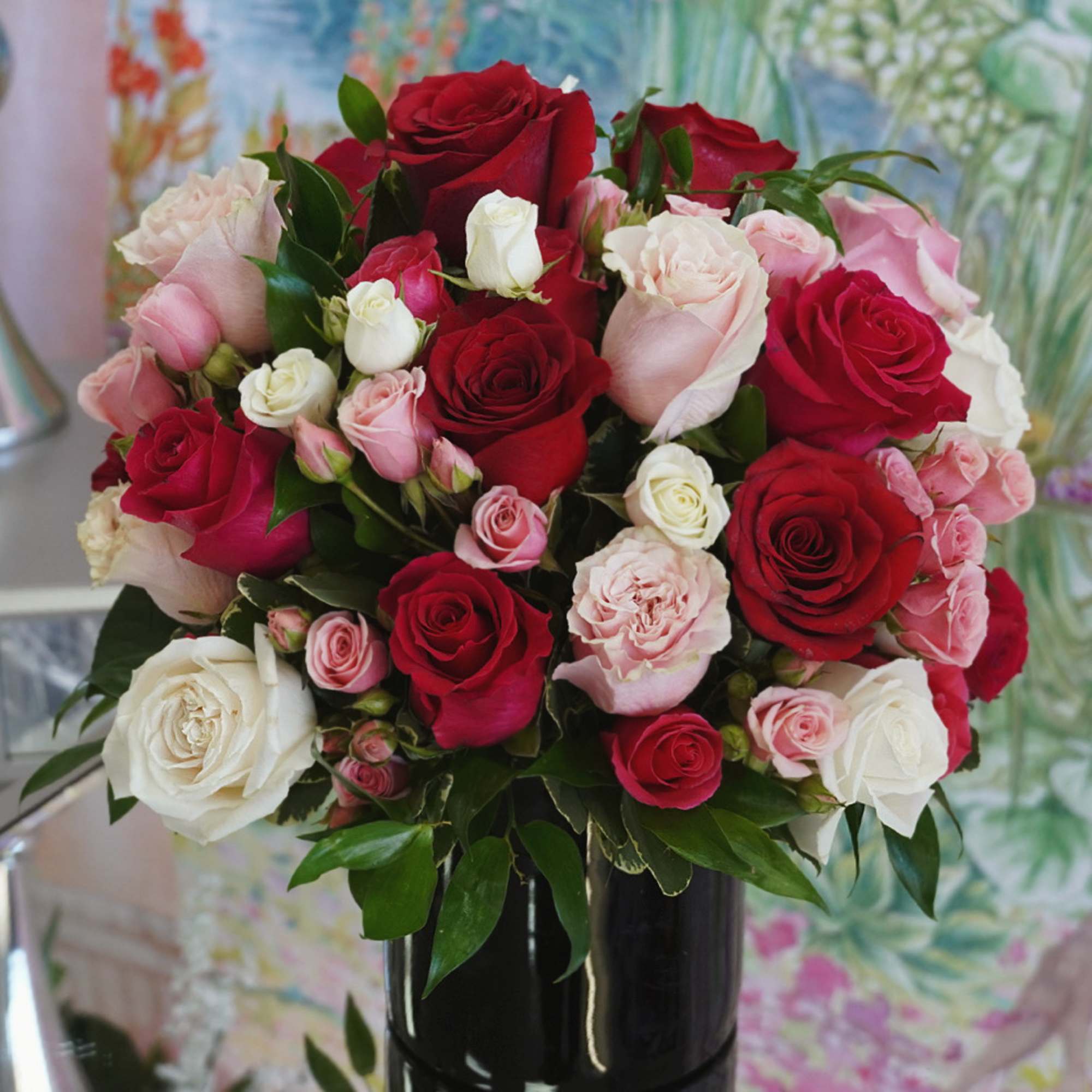 Bouquet of red, pink, and white roses in a black vase