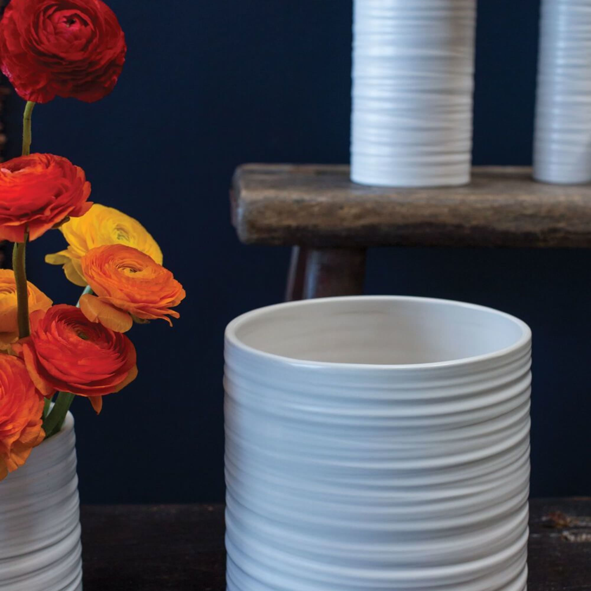 White ribbed ceramic vases with red, orange, and yellow flowers
