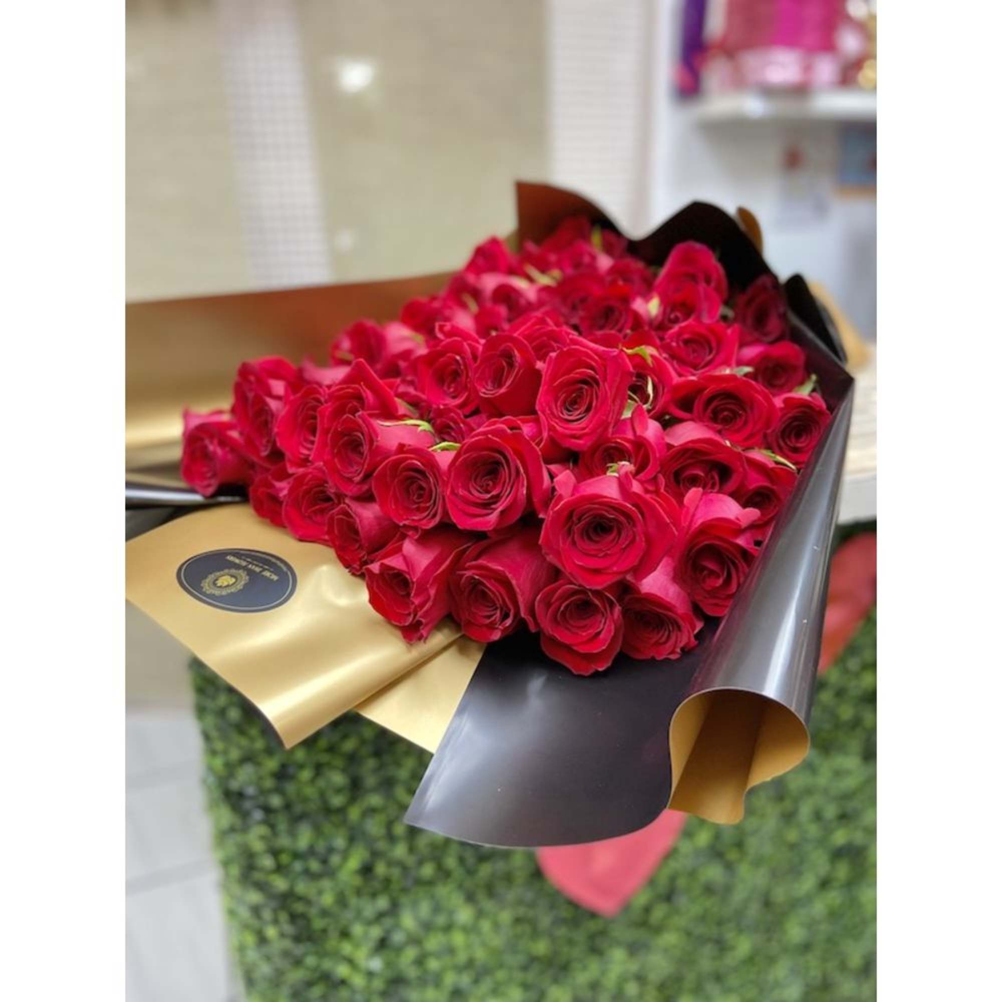 Large bouquet of red roses wrapped in black and gold paper