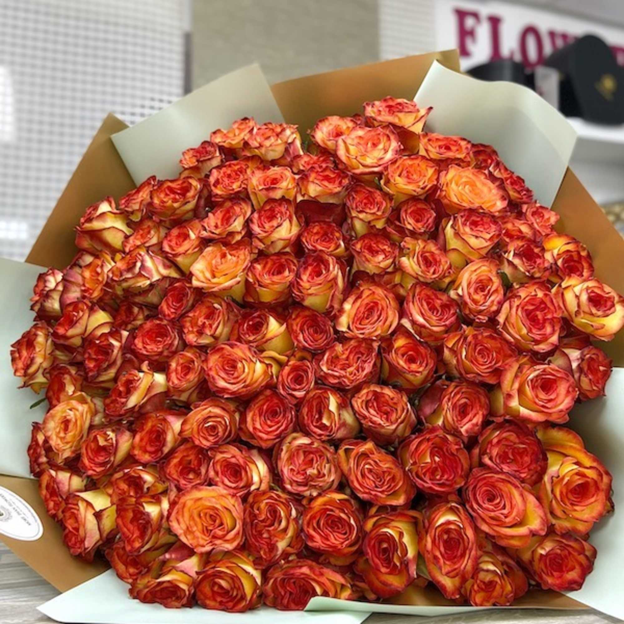 Very large bouquet of orange and red roses wrapped in paper