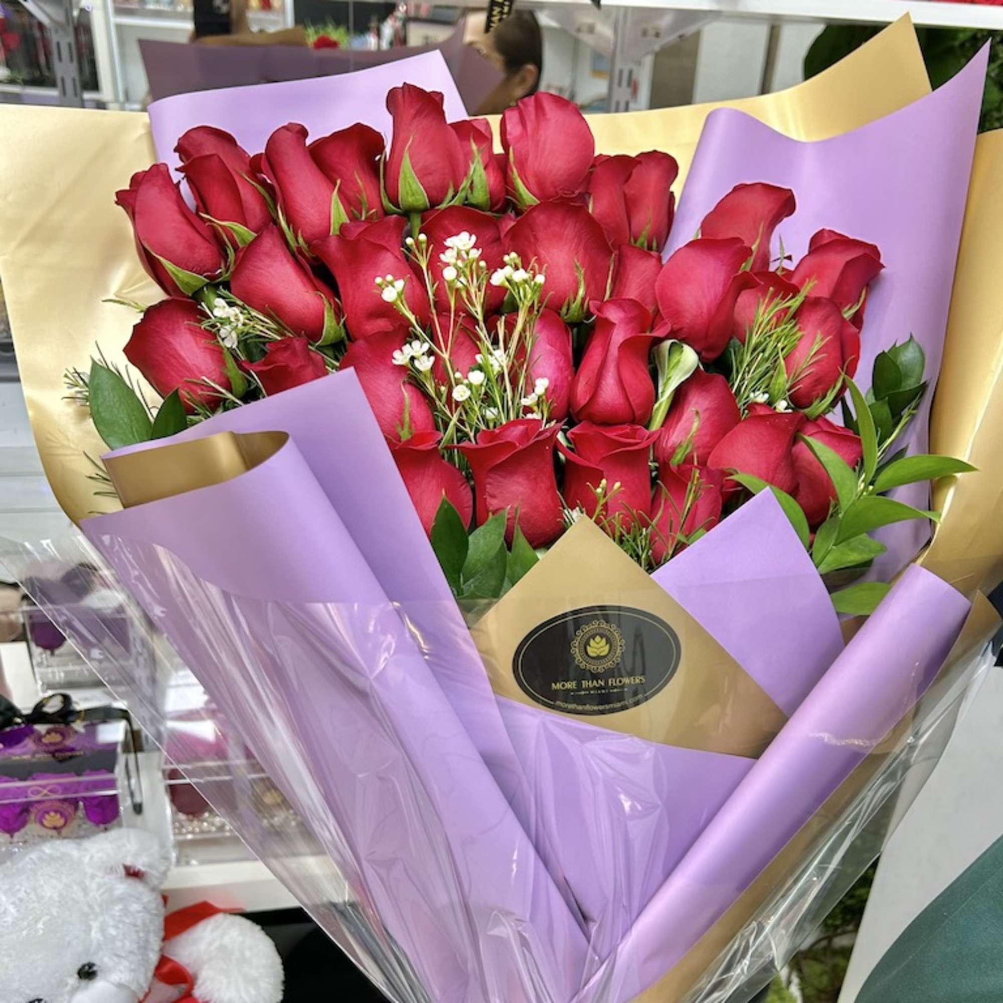 Large bouquet of red roses wrapped in lavender and gold paper with clear cellophane