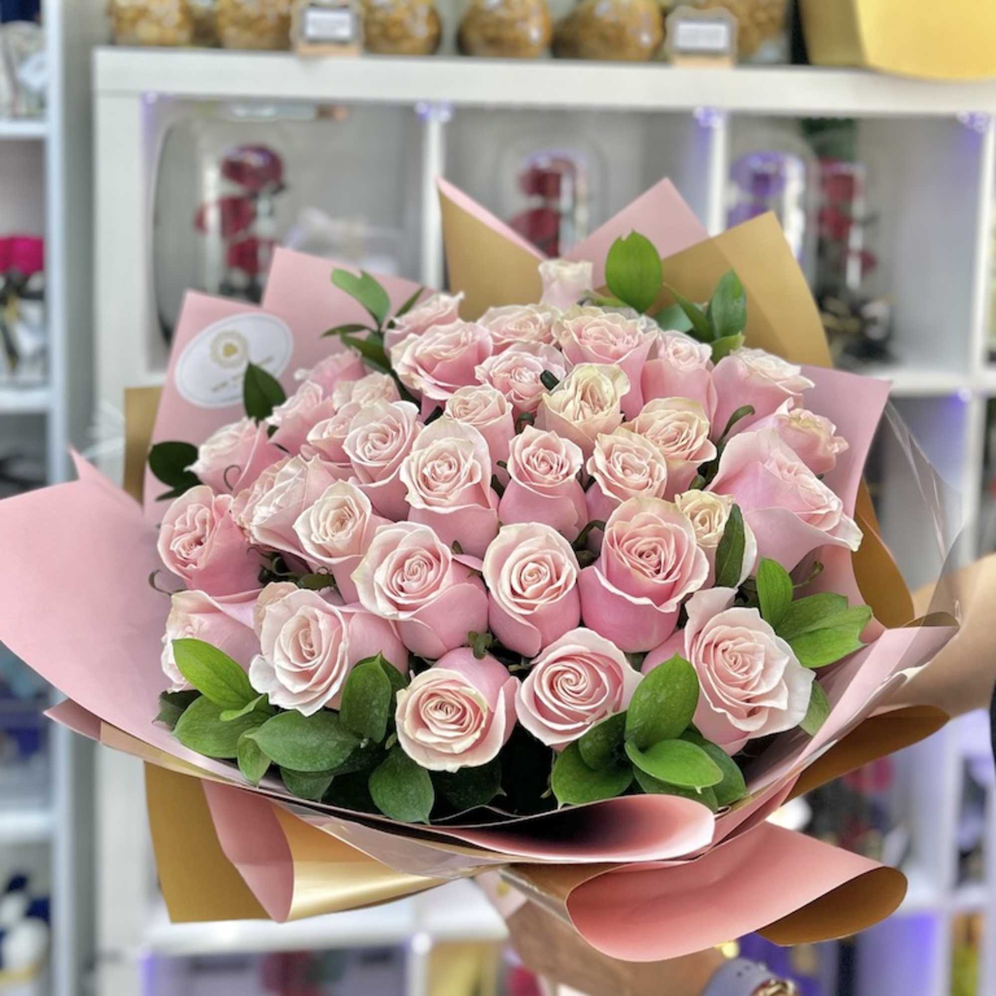 Large hand-tied bouquet of light pink roses wrapped in pink and tan paper