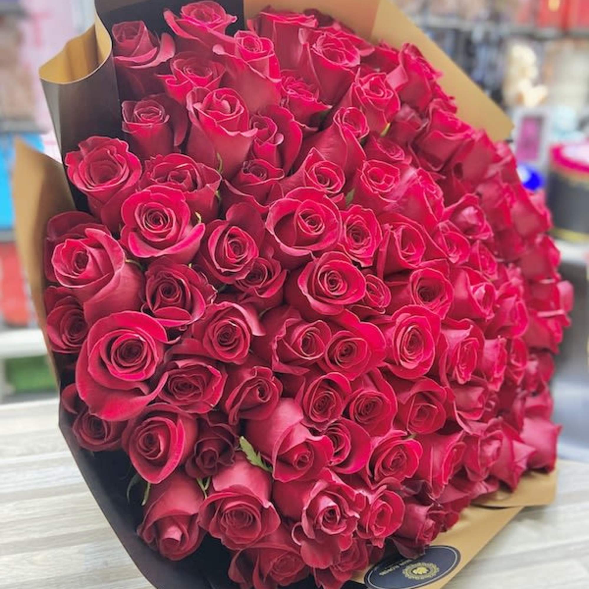Very large bouquet of red roses wrapped in brown and black paper on a table