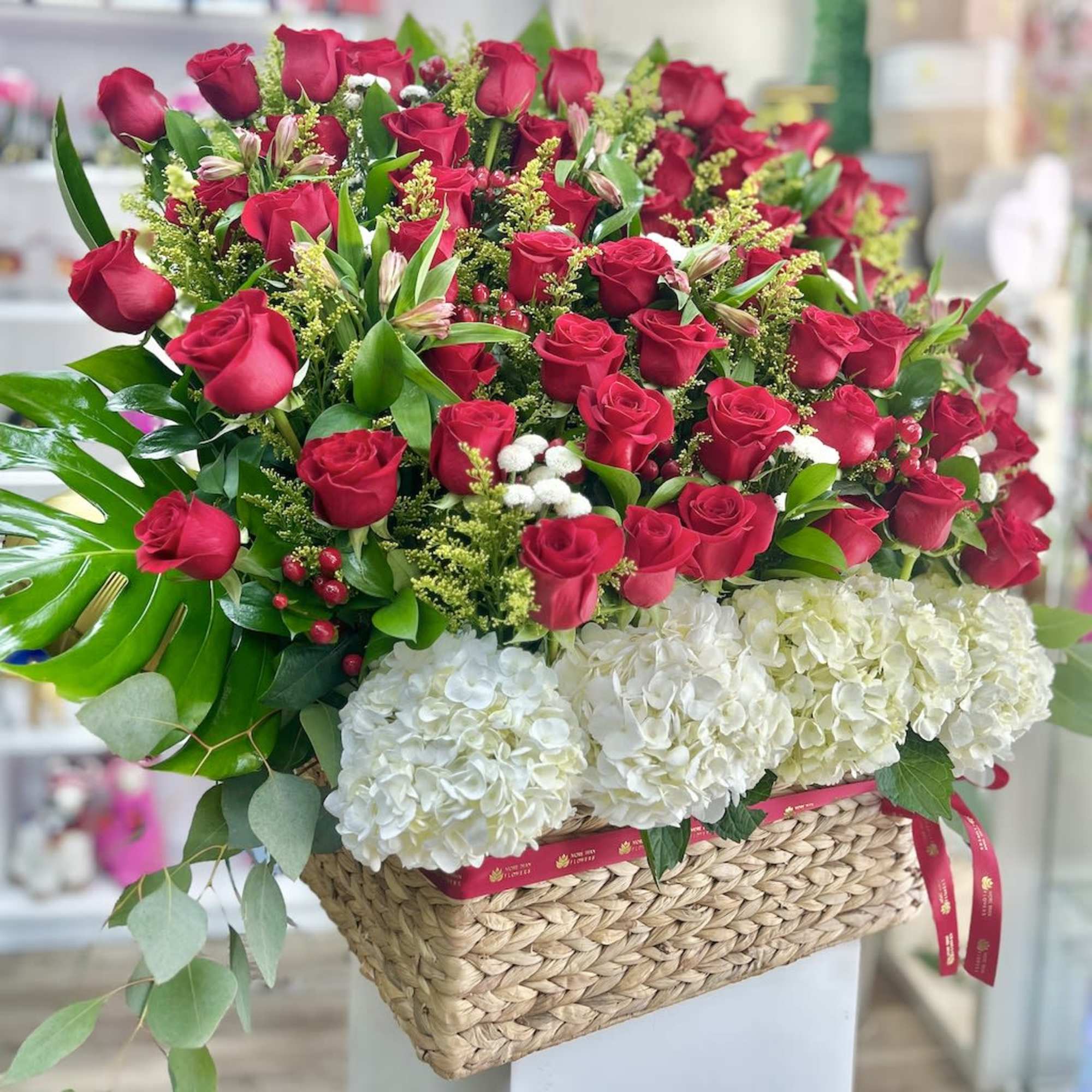 Large basket arrangement of red roses and white hydrangeas.