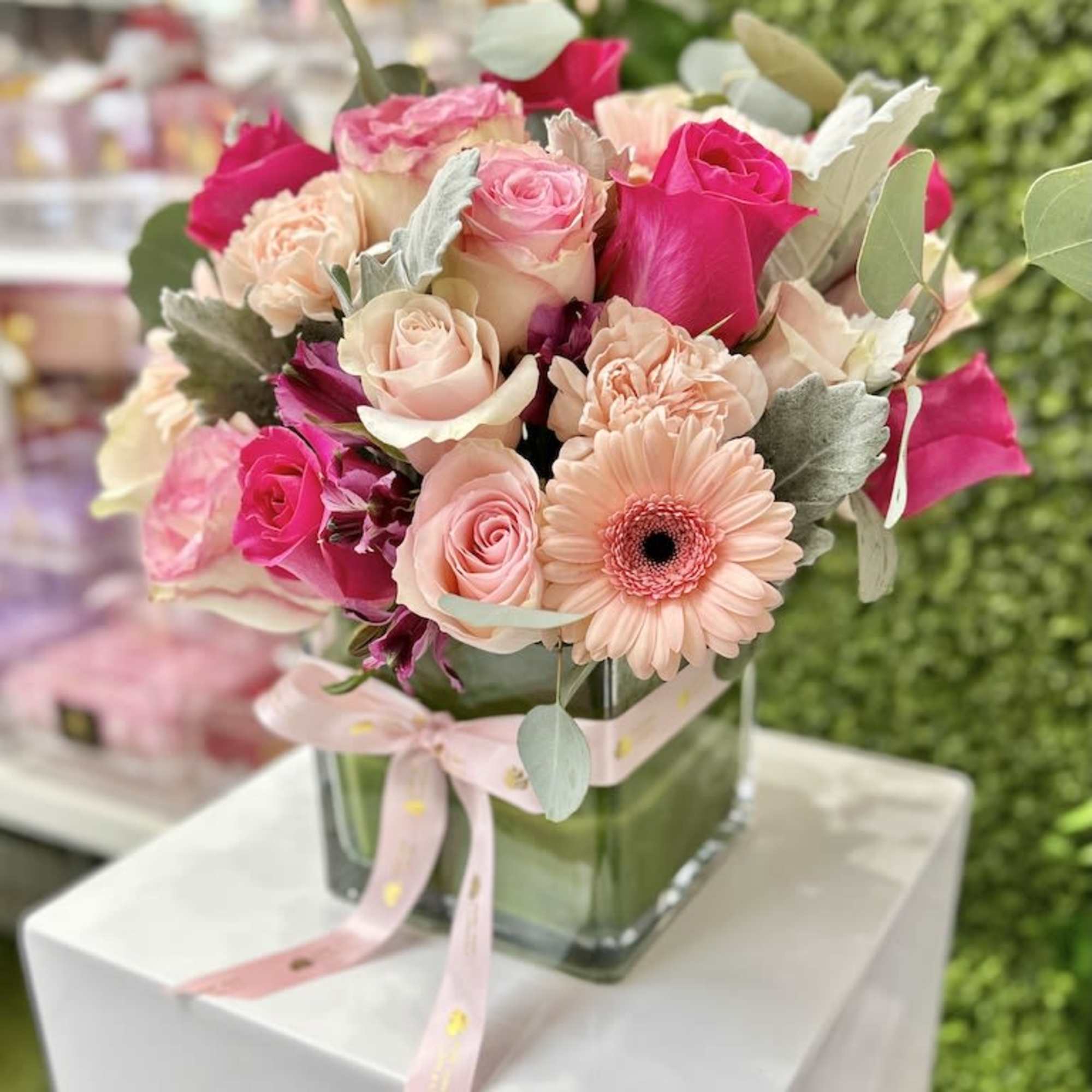 Pink and peach rose arrangement with gerbera daisies in a glass cube vase with ribbon
