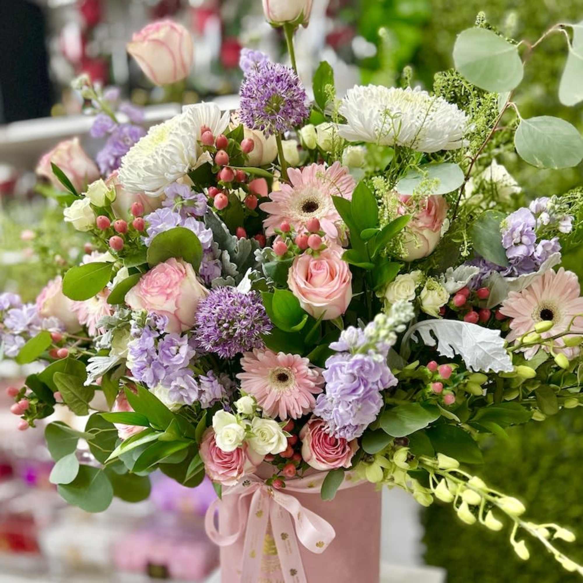 Pastel bouquet of pink roses, gerbera daisies, and white mums in a pink hatbox with ribbon