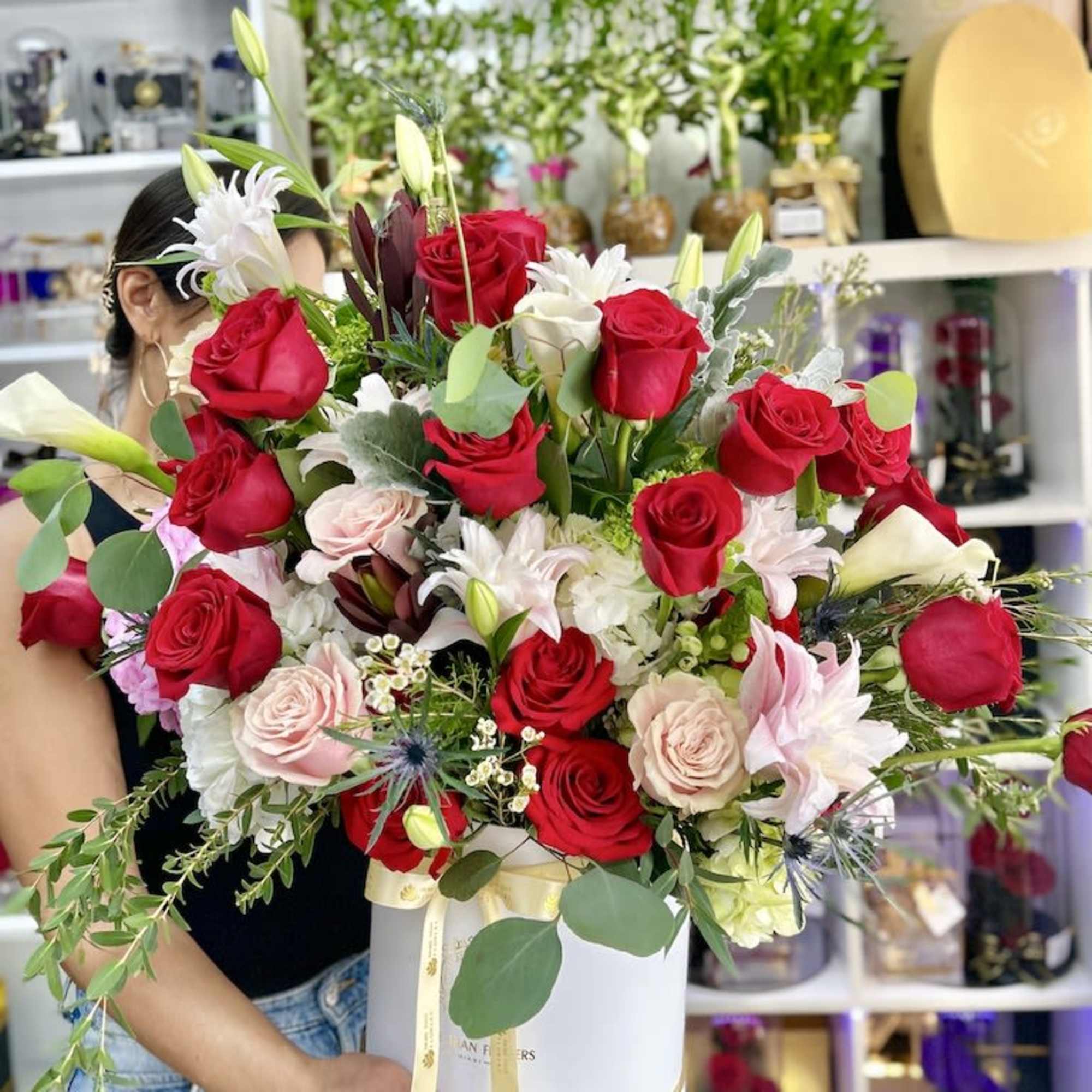 Large arrangement of red and blush roses with mixed blooms in a white hat box.