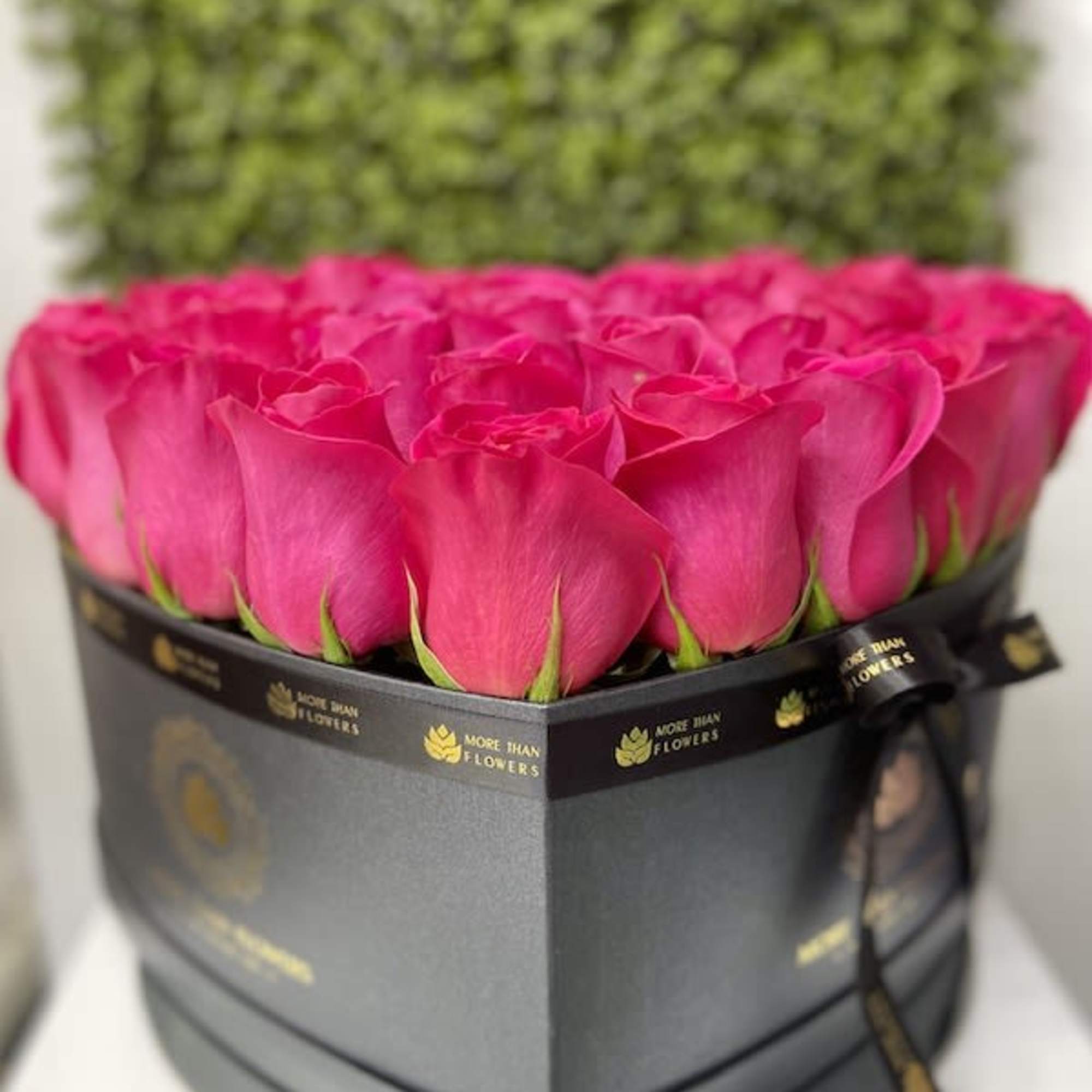 Heart-shaped black hatbox filled with bright pink roses