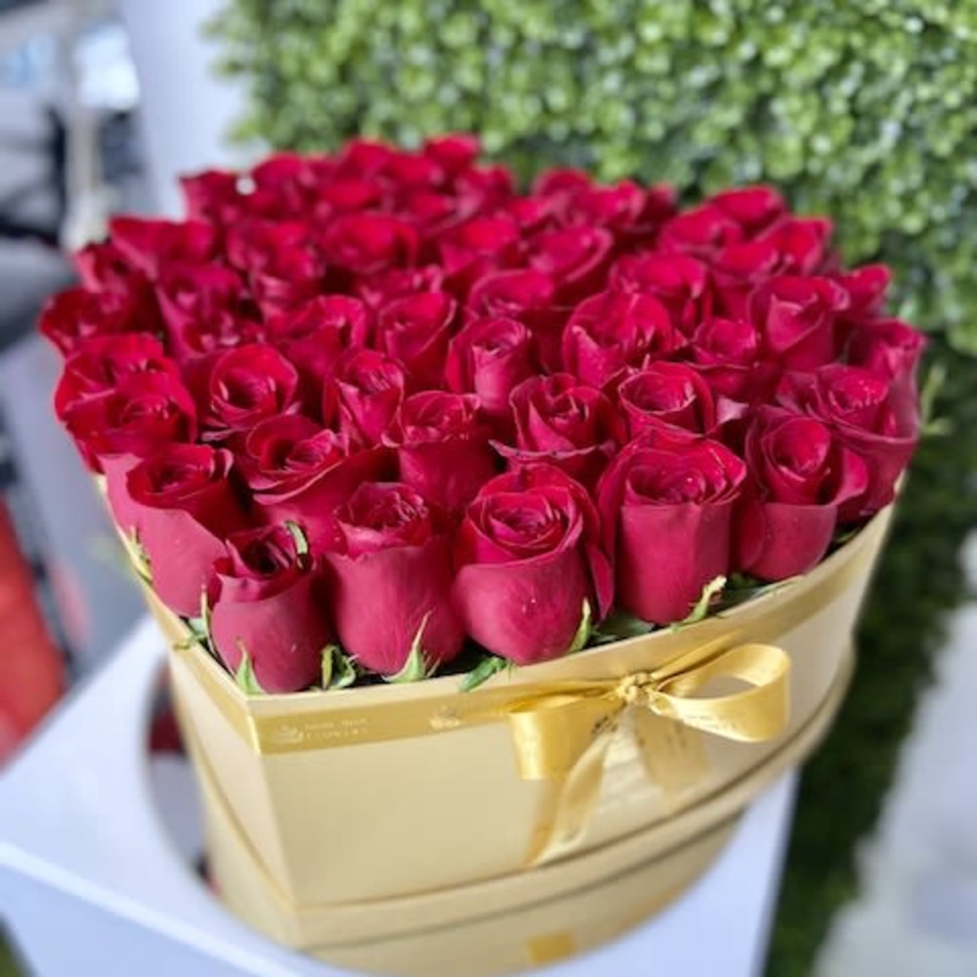 Heart-shaped gold box filled with red roses and tied with a gold ribbon