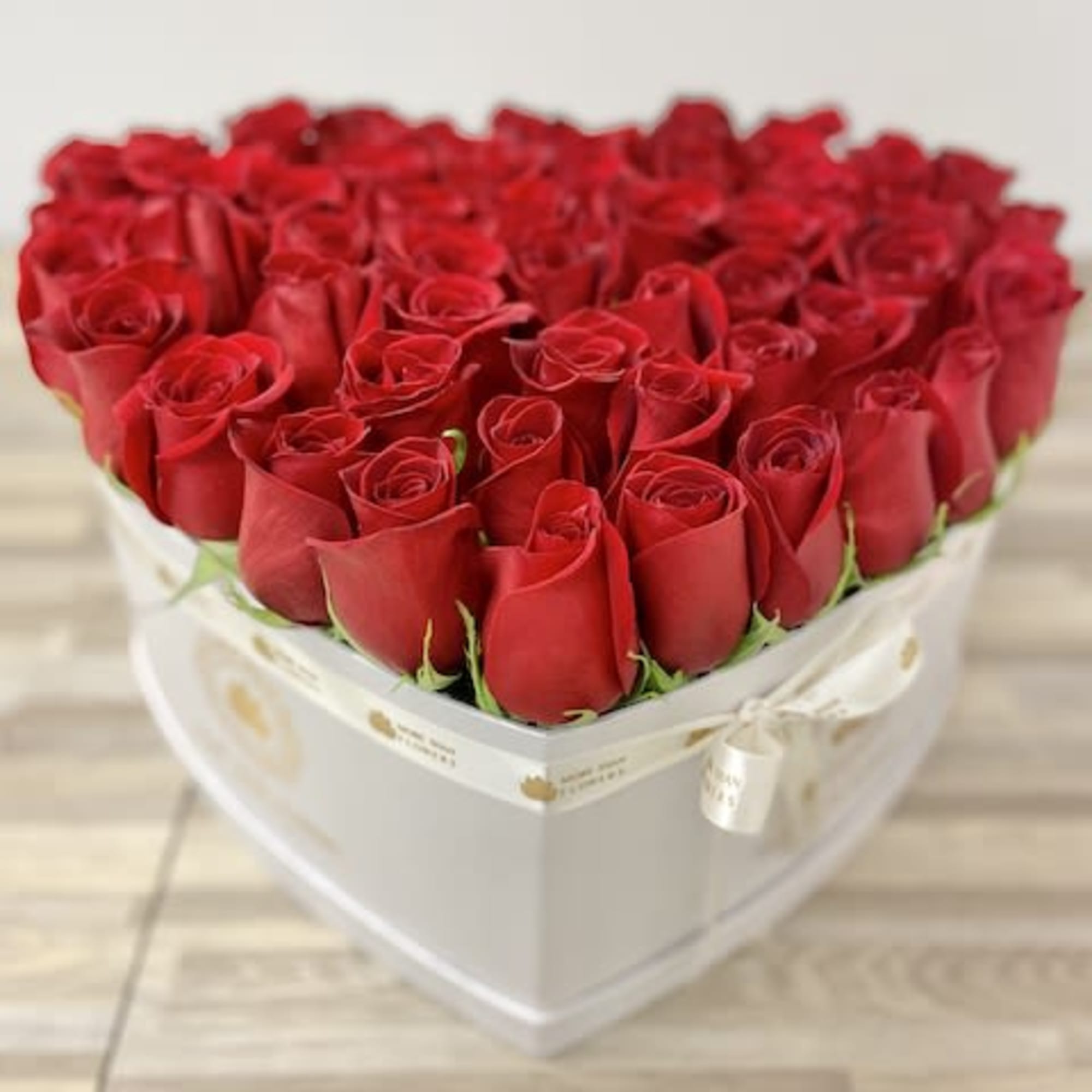 Heart-shaped white box filled with tightly packed red roses