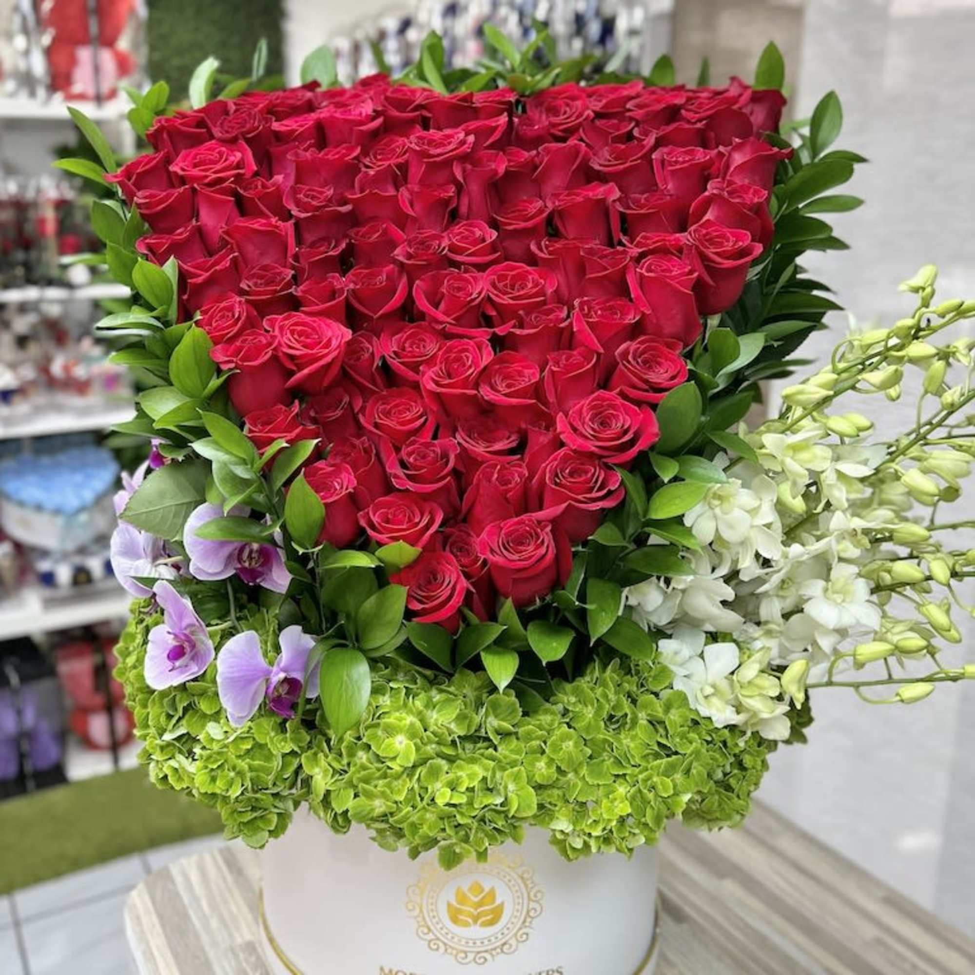 Large red rose hatbox arrangement with green hydrangeas and white and purple orchids