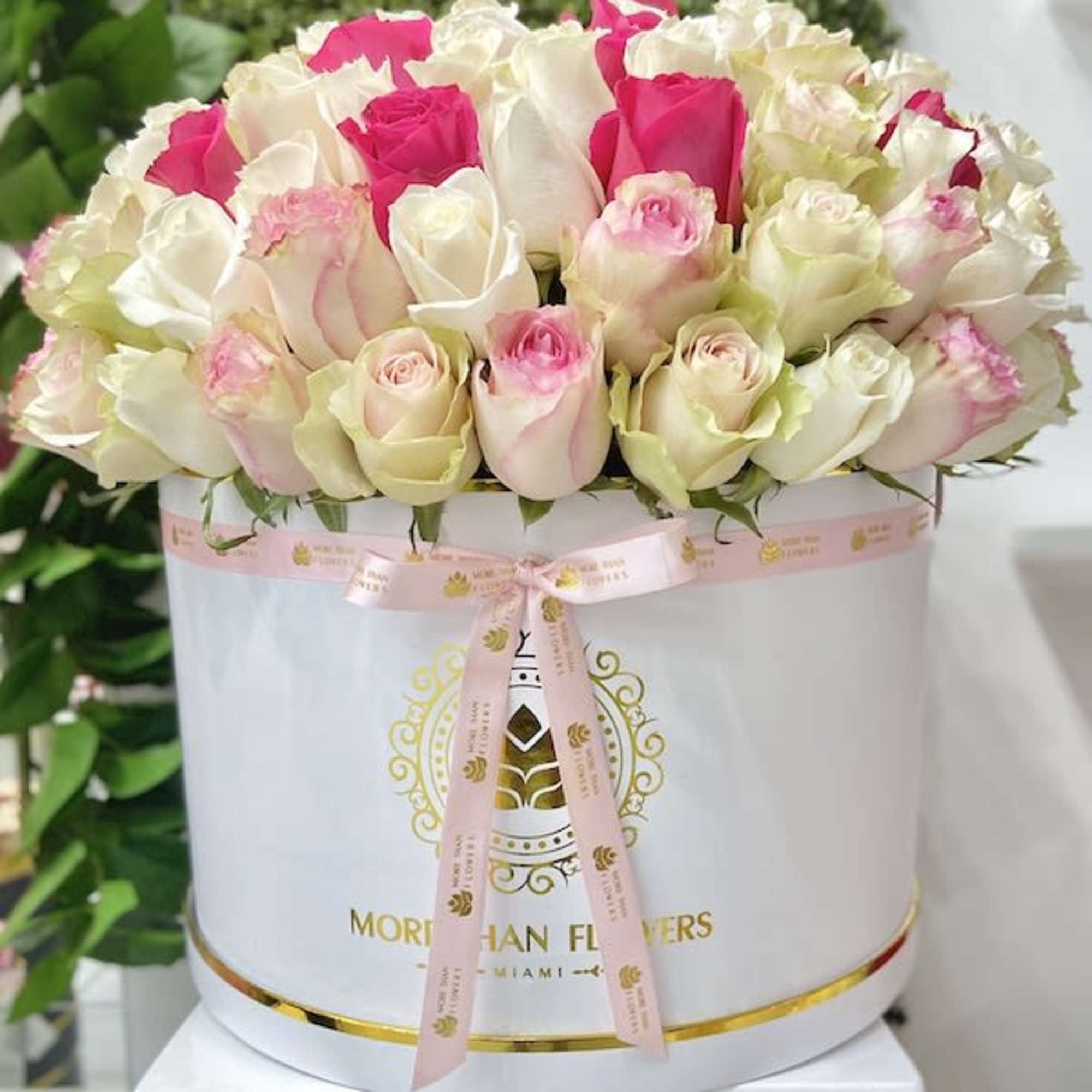 Round box of cream and pink roses with hot pink accents and a pink ribbon bow