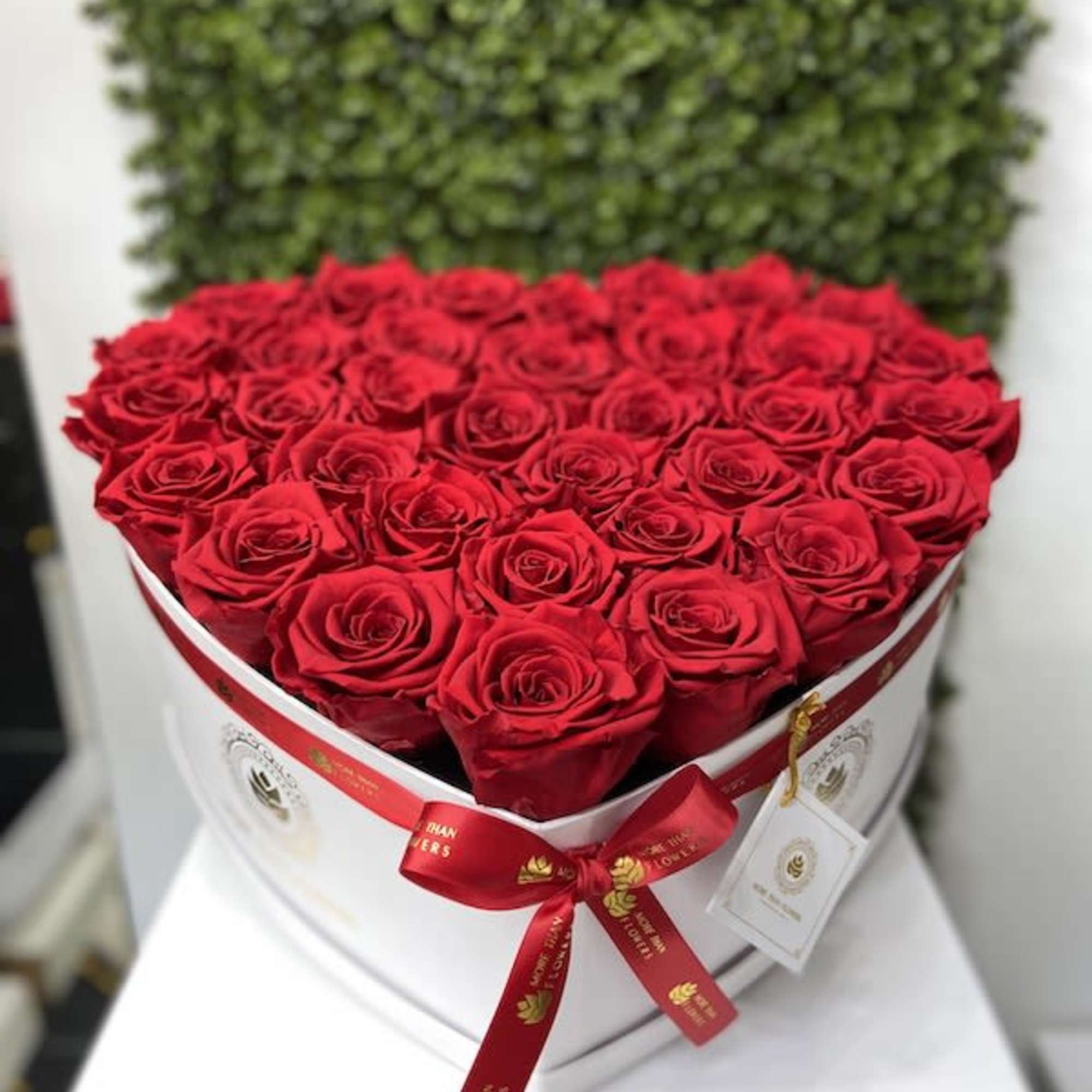 Heart-shaped white box filled with red roses and tied with a red ribbon