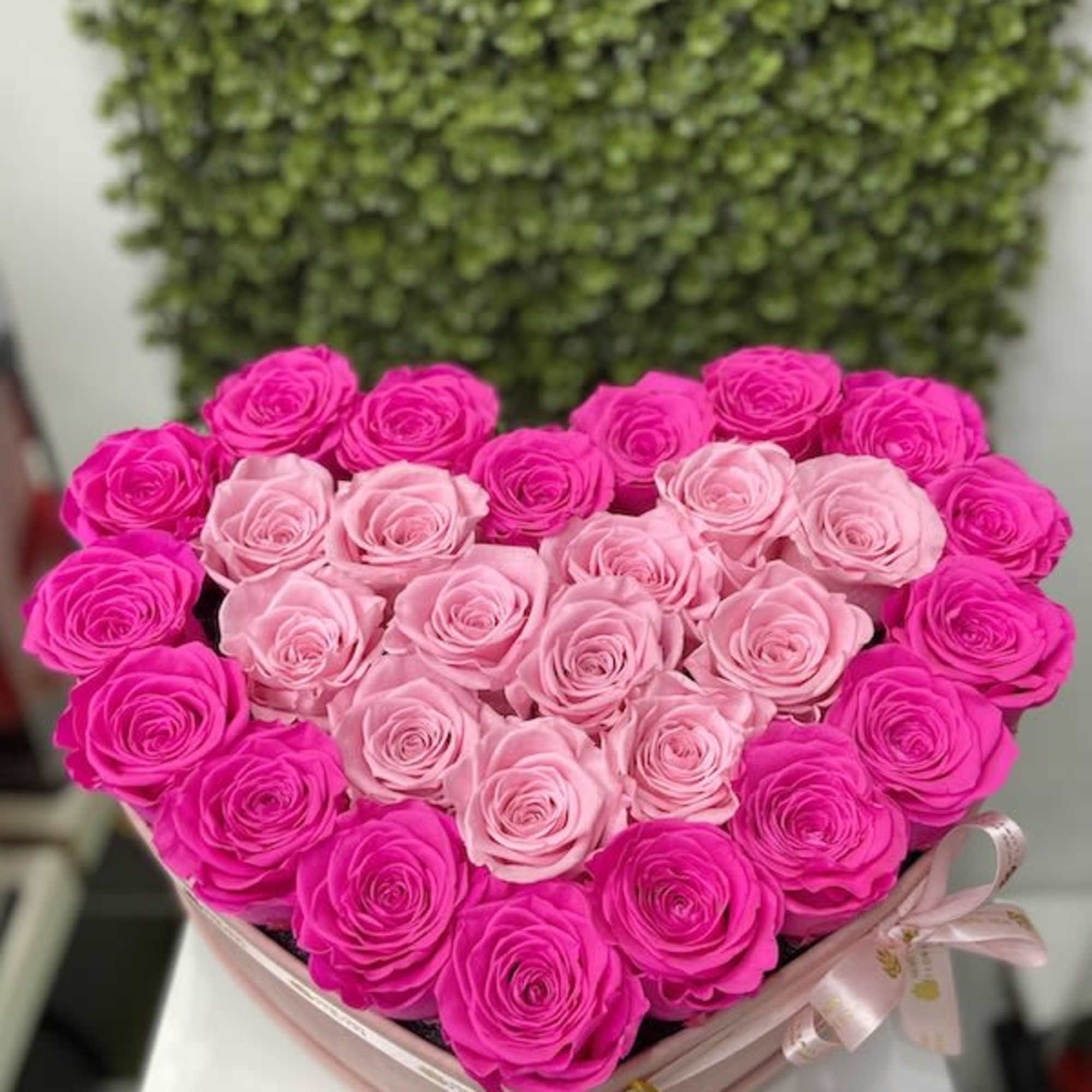 Heart-shaped box of bright and light pink roses arranged in concentric rings