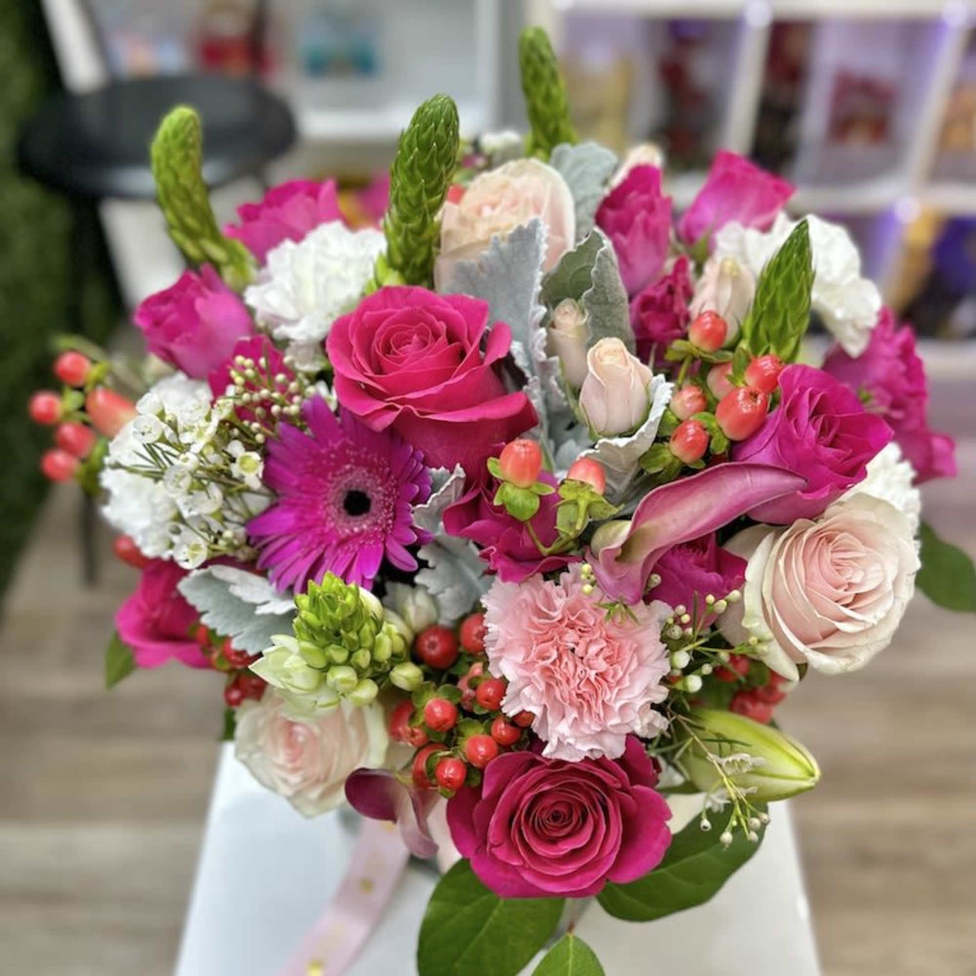 Mixed bouquet of hot pink and blush flowers arranged in a glass vase with ribbon