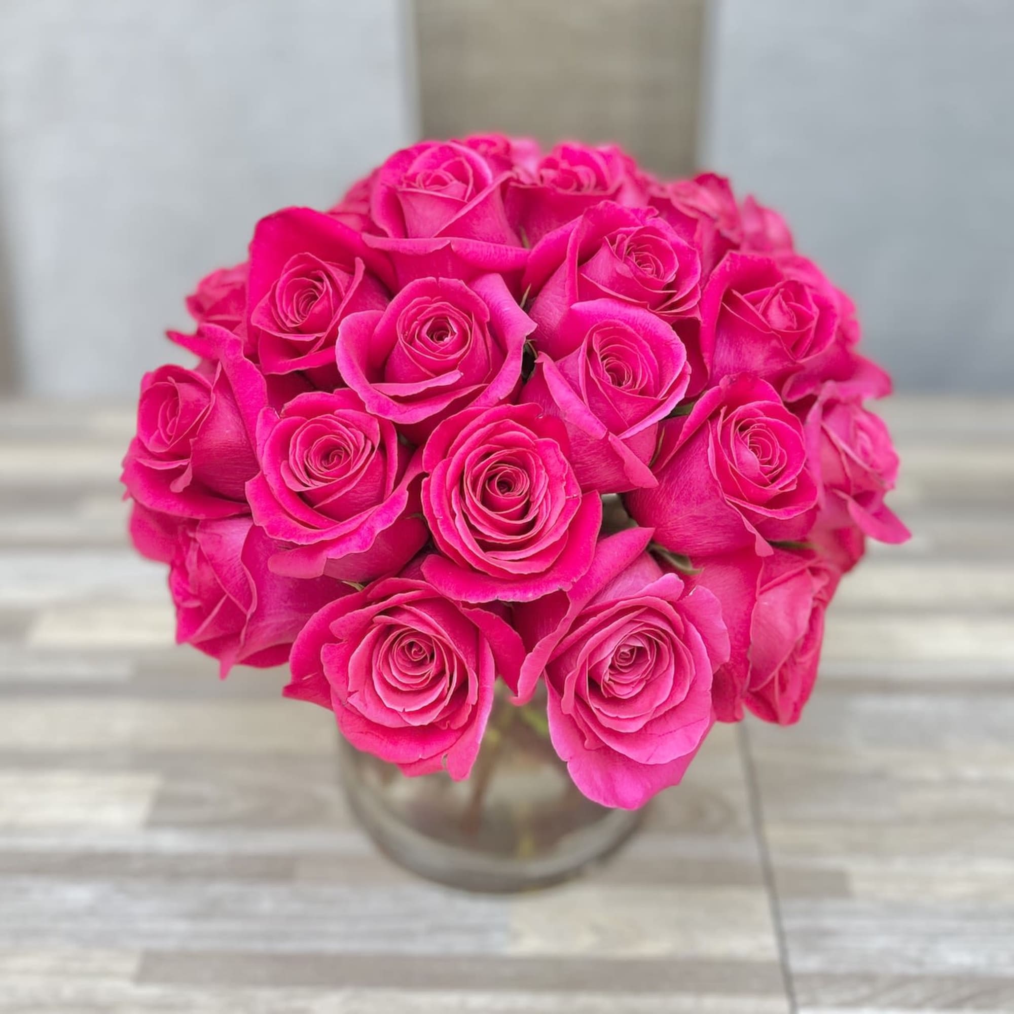 Compact arrangement of hot pink roses in a clear glass vase