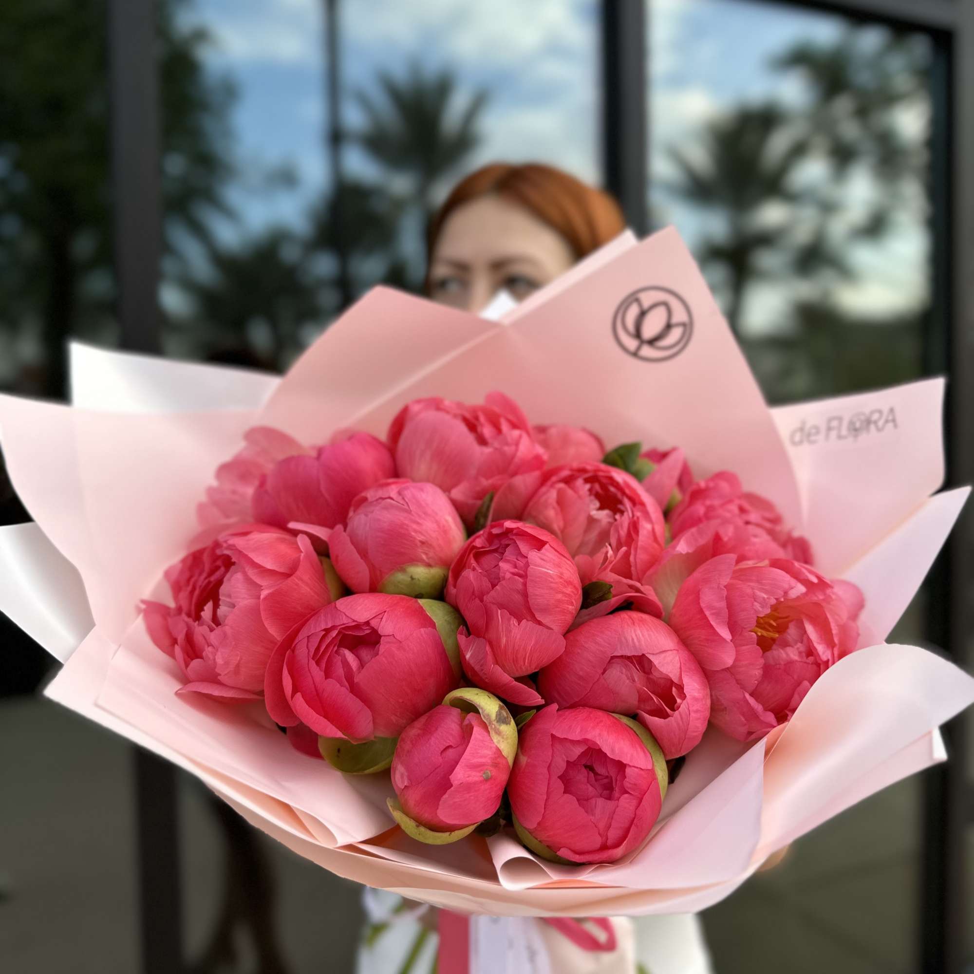 Bouquet of bright pink peonies wrapped in pale pink paper