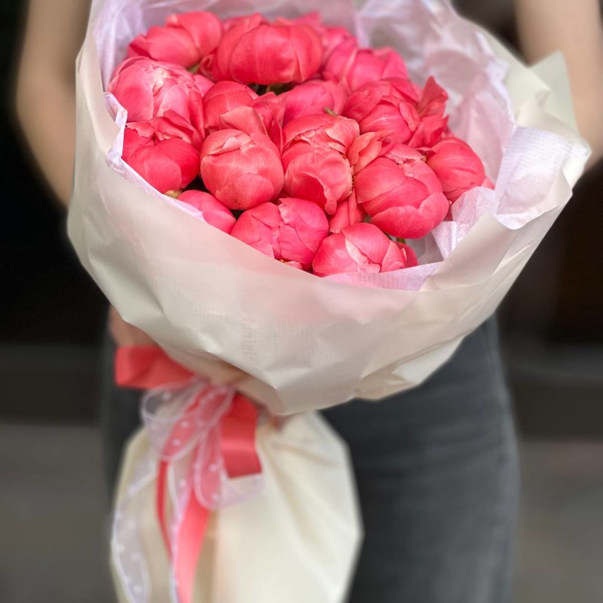 Bouquet of bright pink peonies wrapped in white paper