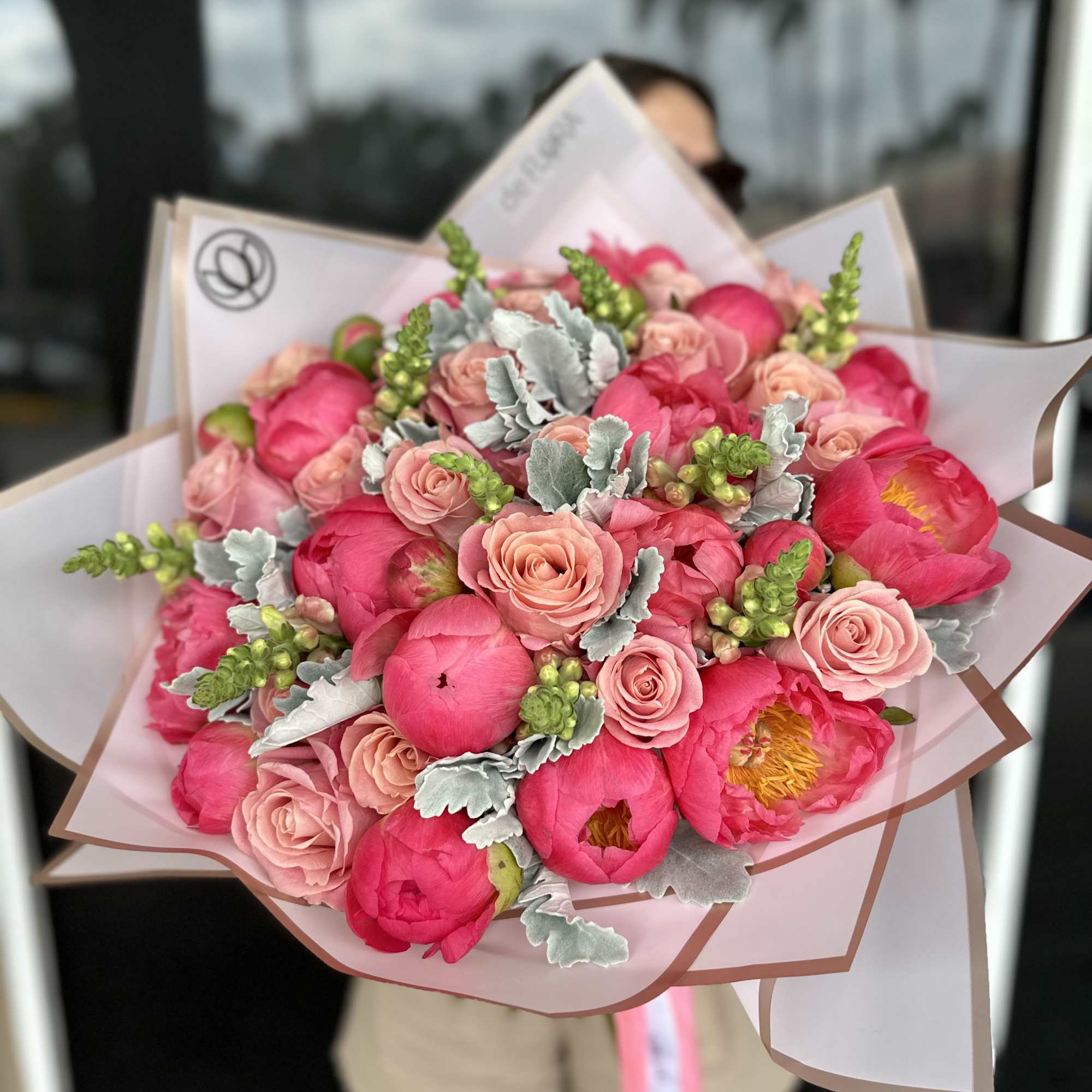 Bouquet of pink peonies and blush roses wrapped in pale paper