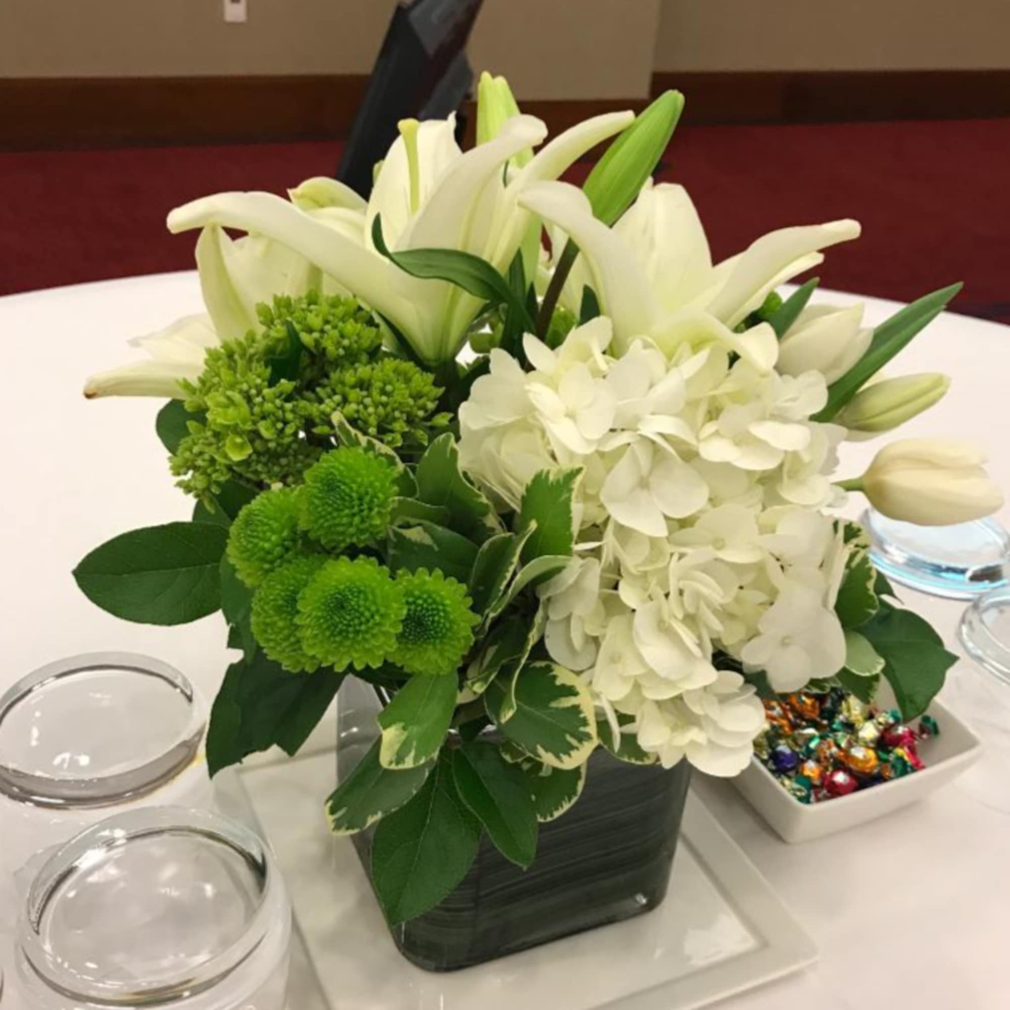 White lilies and hydrangeas with green mums in a square vase