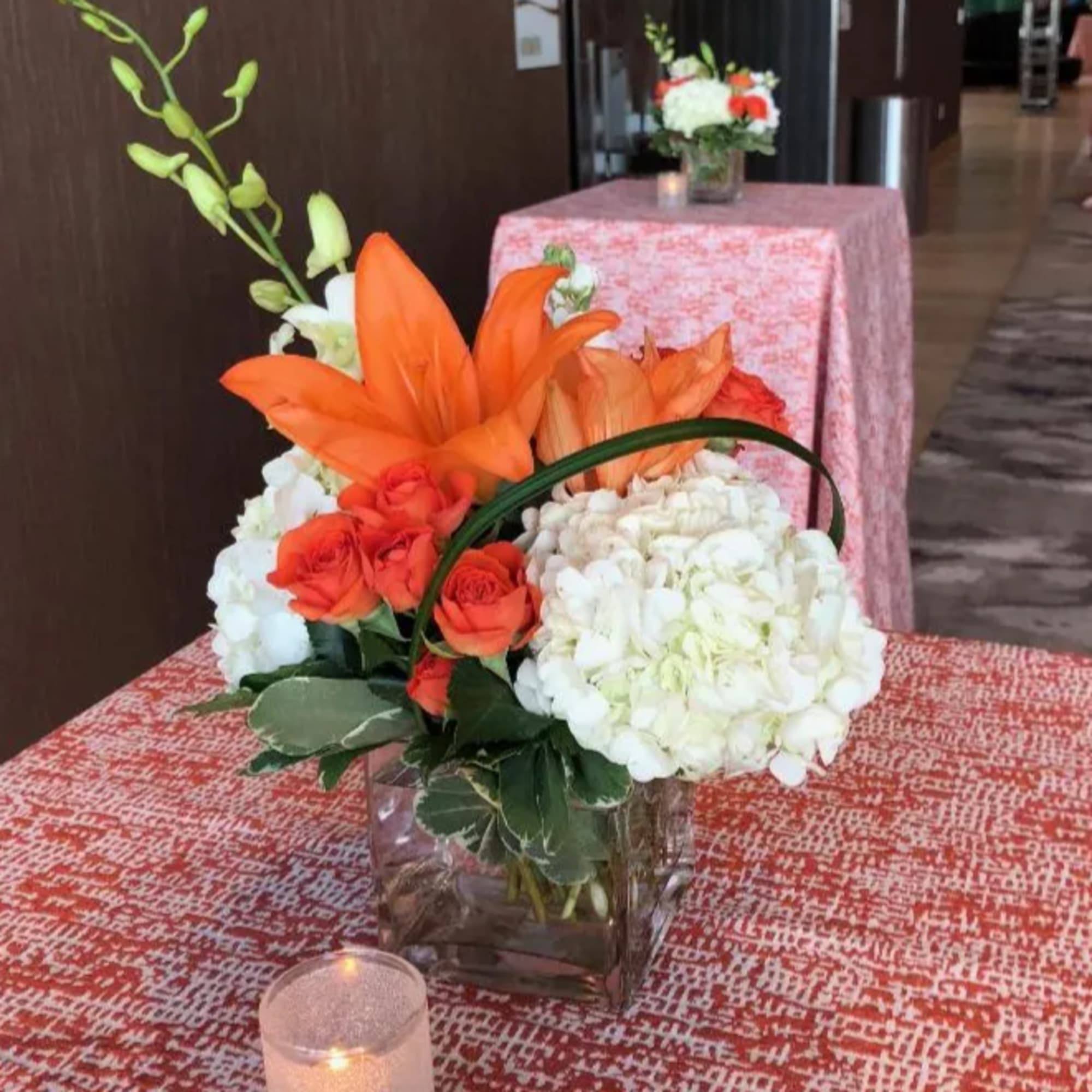 Orange lilies and roses with white hydrangeas in a glass vase
