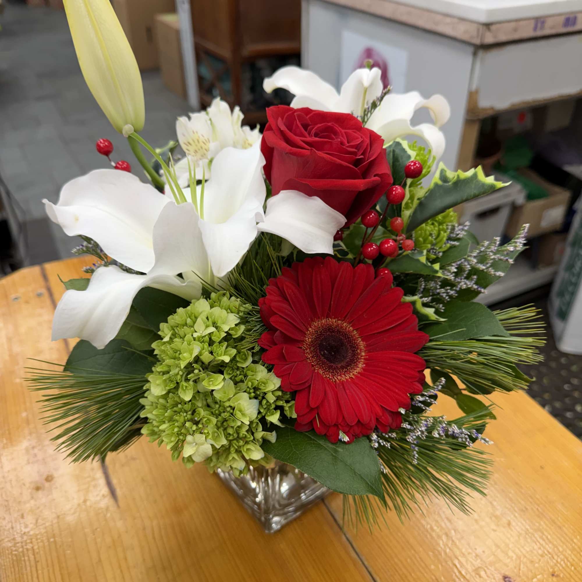 Red rose and gerbera bouquet with white lilies in a glass vase