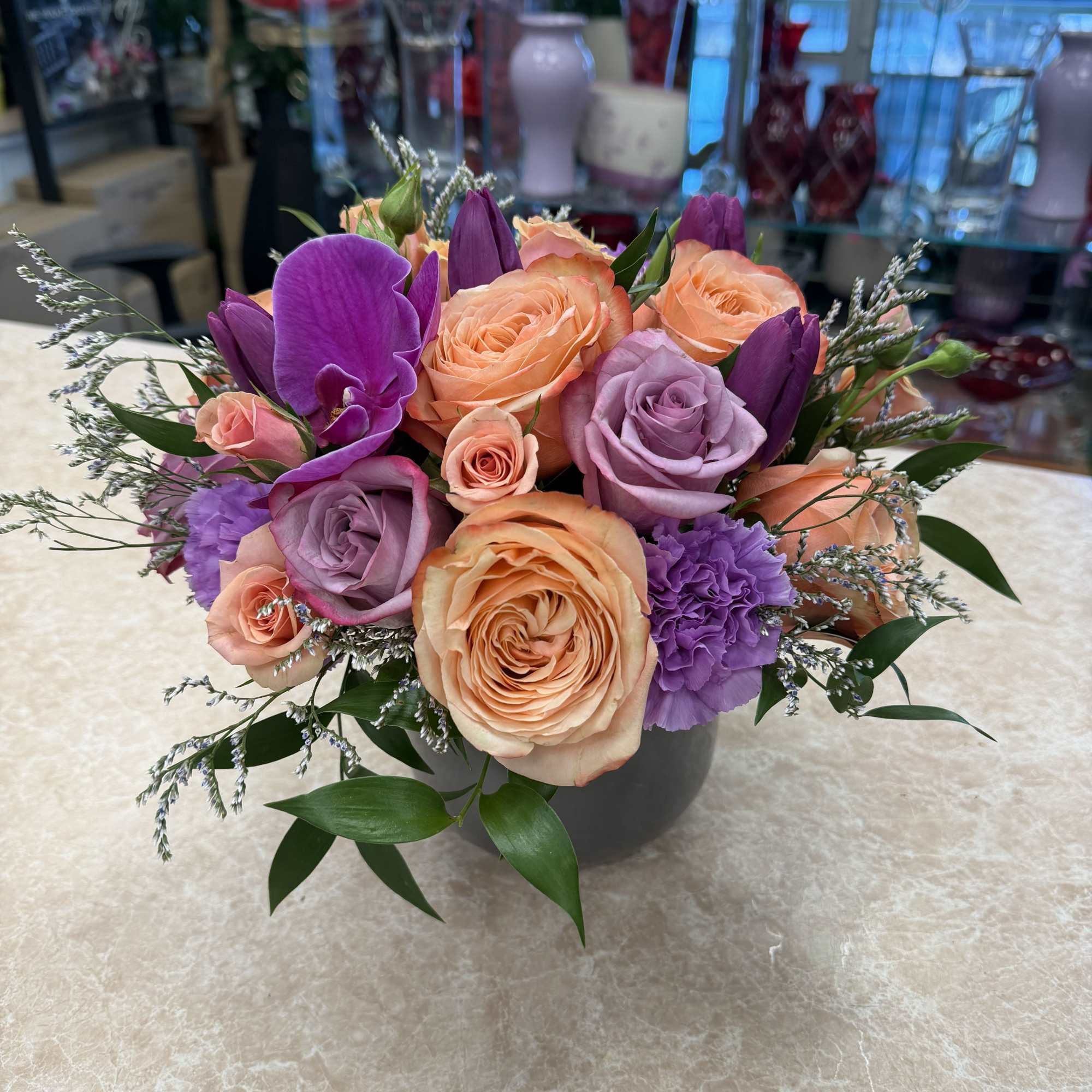 Peach and lavender rose bouquet in a gray vase