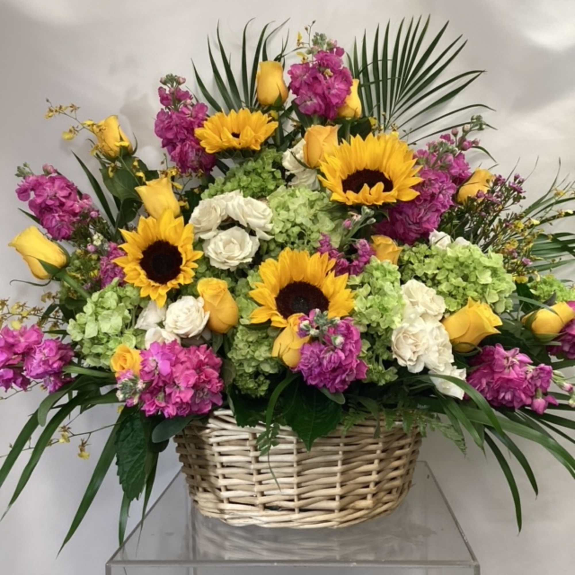 Basket arrangement with sunflowers, yellow roses, white blooms, and pink flowers