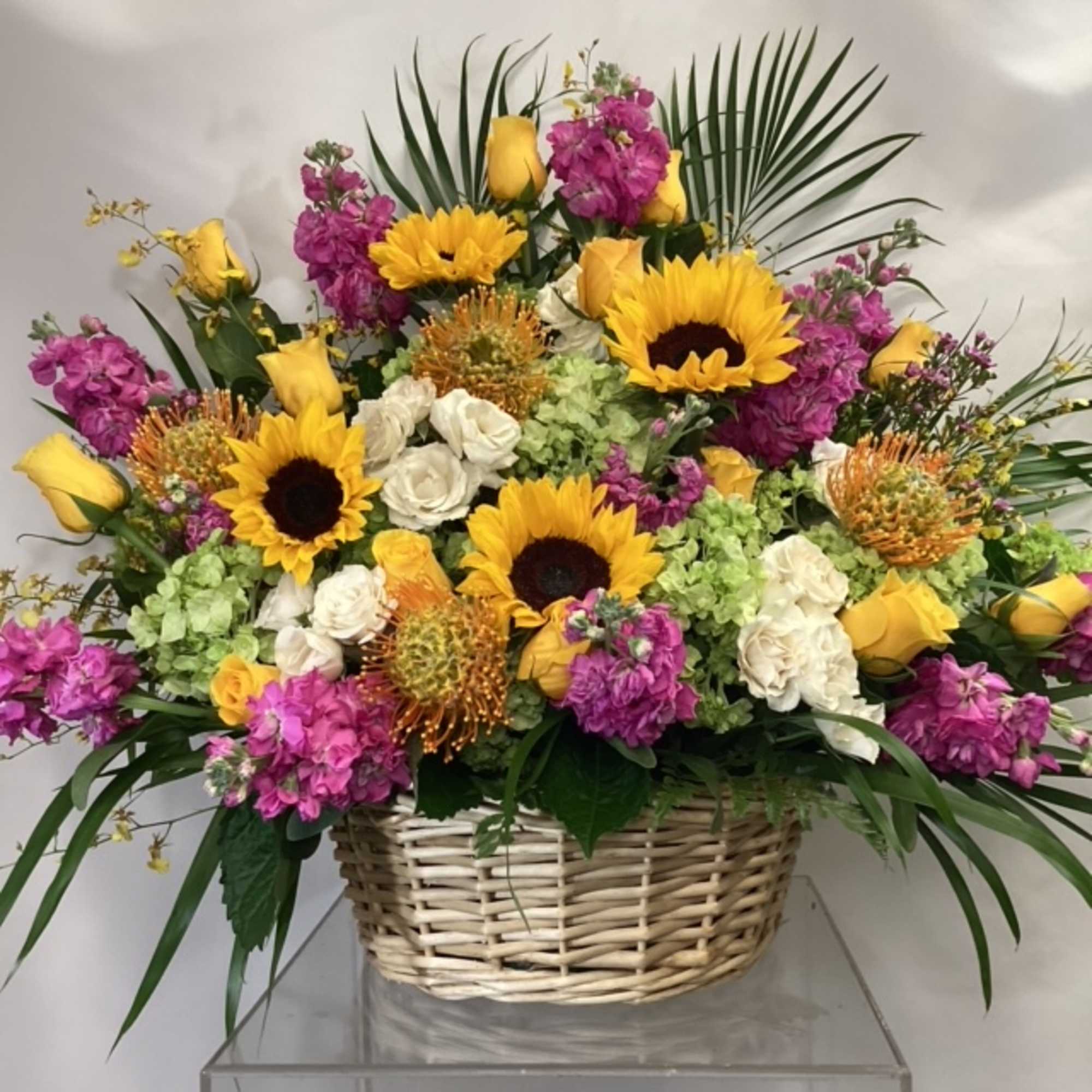 Basket arrangement with sunflowers, yellow roses, and pink flowers