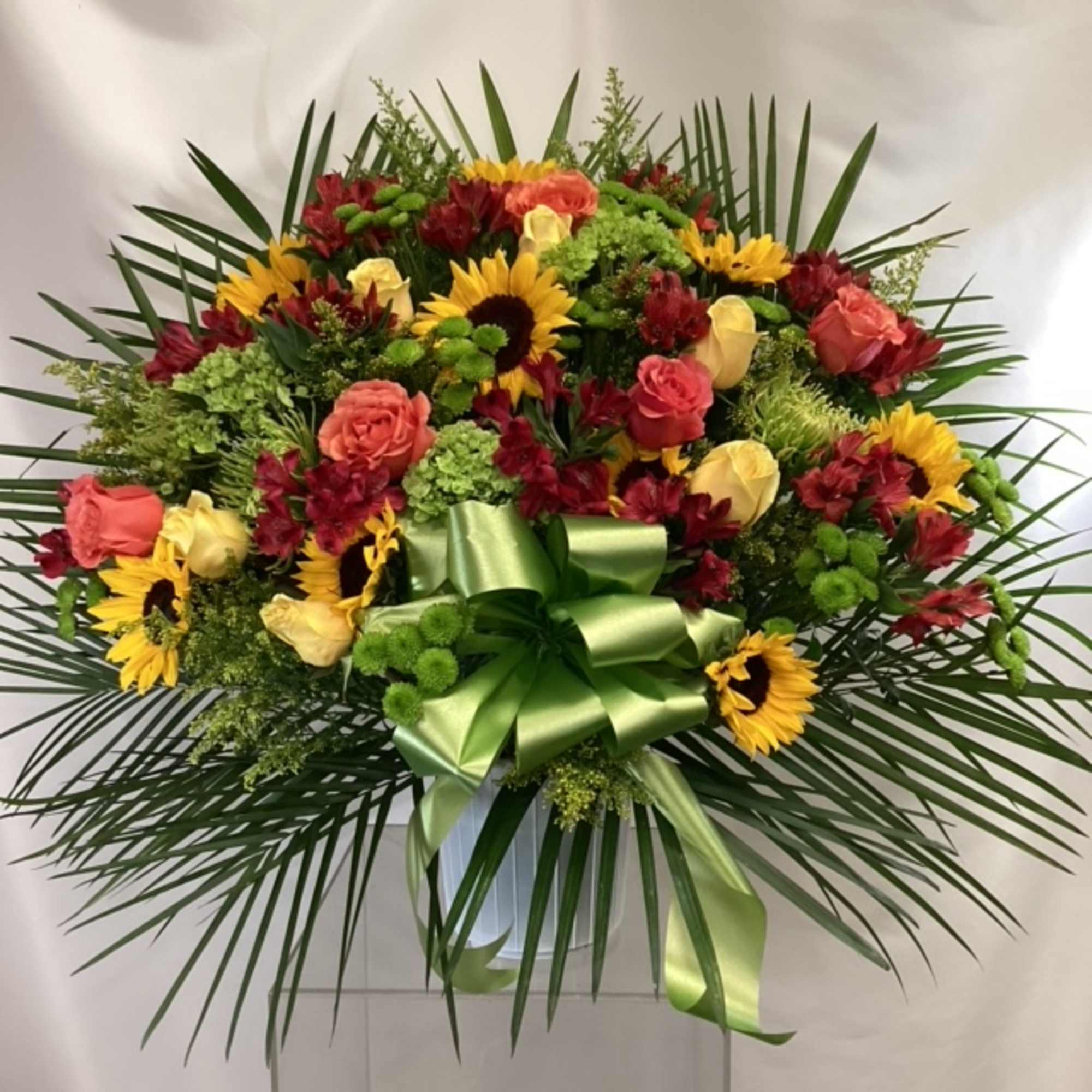Large mixed flower arrangement with sunflowers and roses in a vase