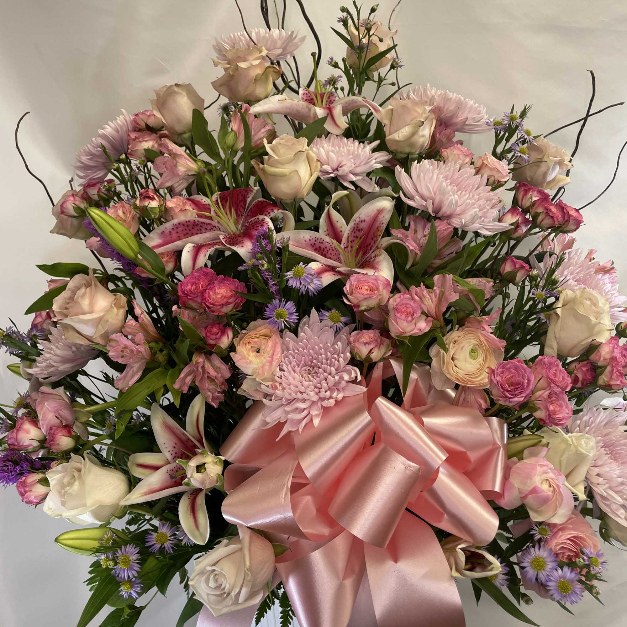 Large pink and white floral arrangement with a satin bow in a white vase