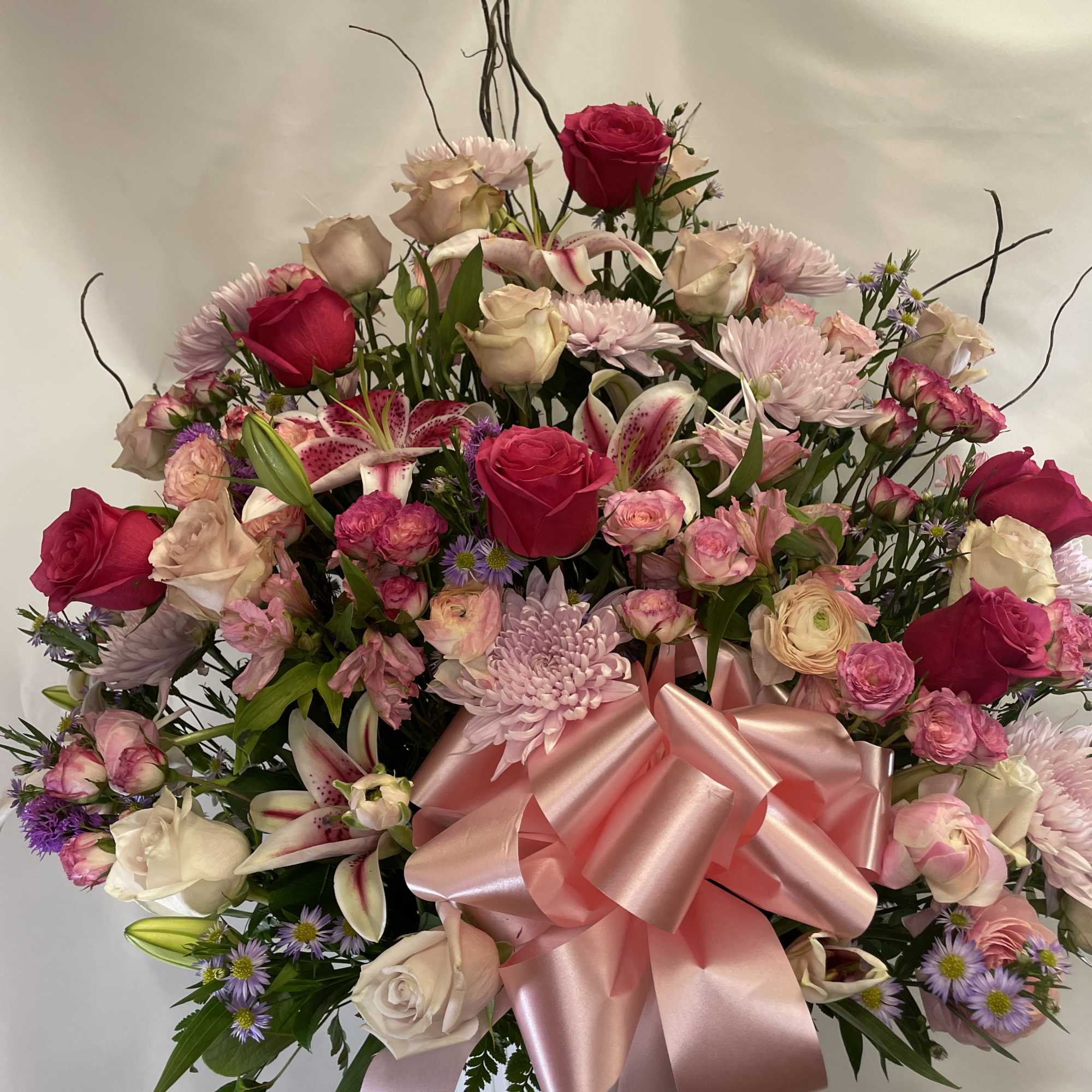Large pink and white floral arrangement with a satin bow in a white vase