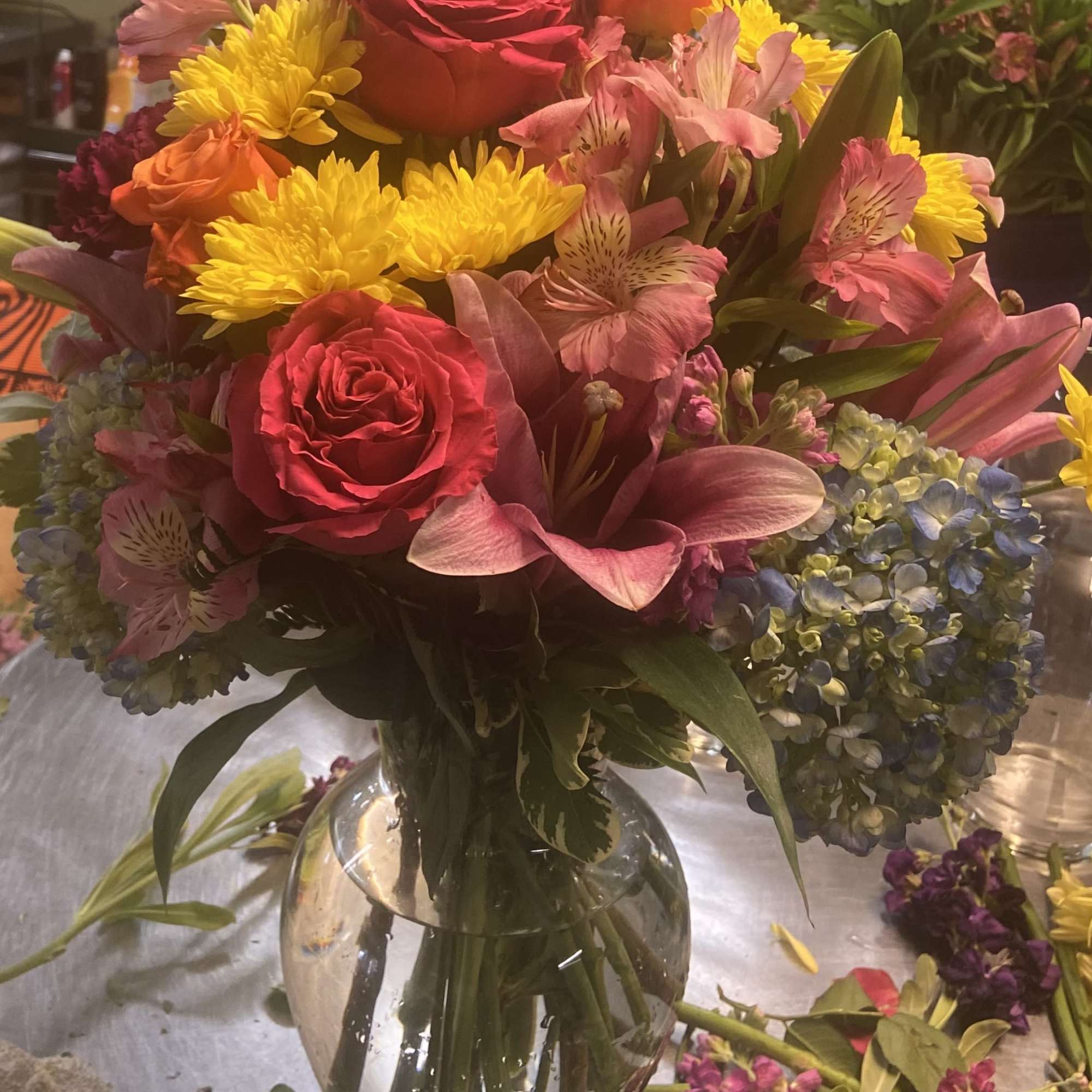Mixed bouquet of roses, lilies, chrysanthemums, and hydrangeas in a glass vase