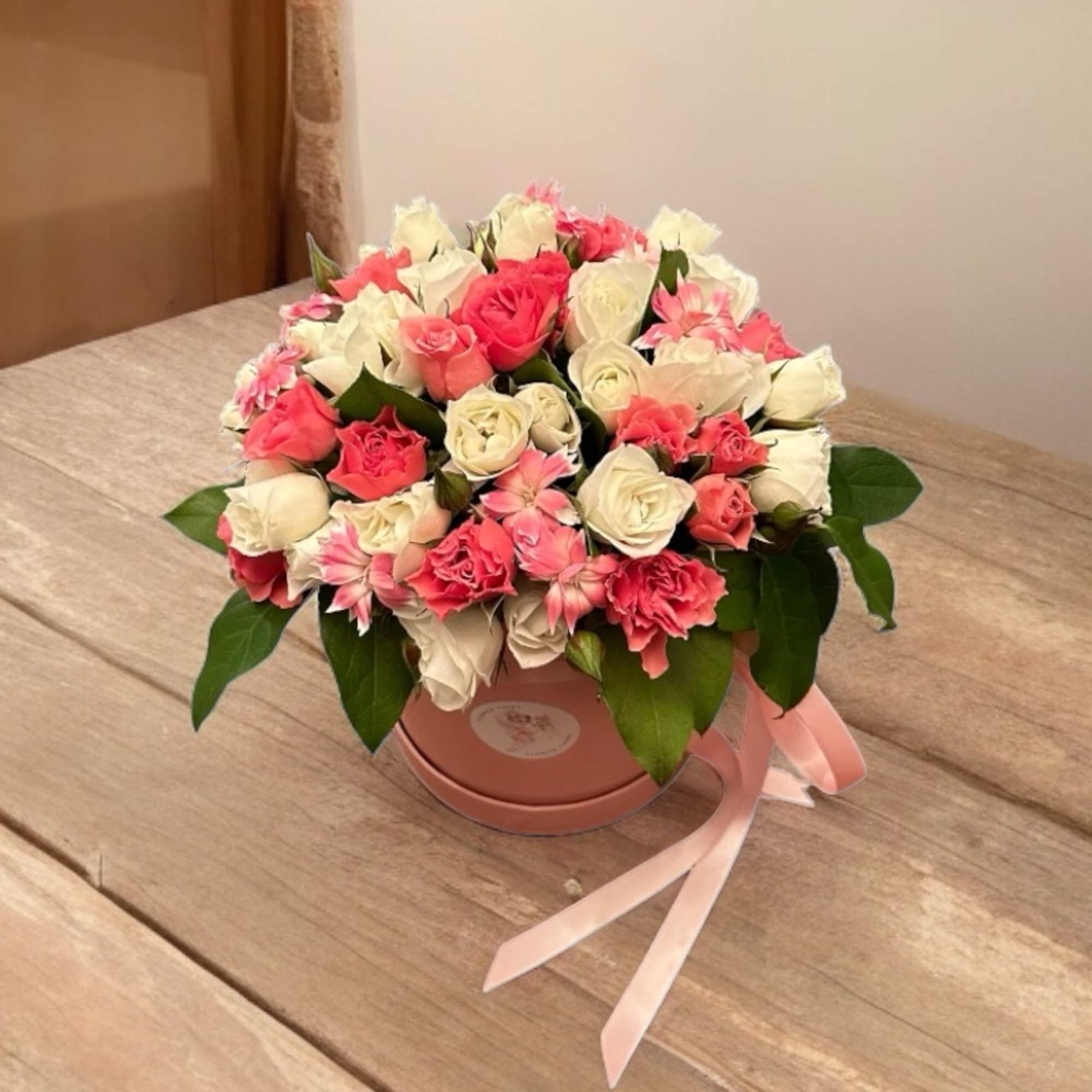 Pink and white rose bouquet in a round hatbox with a ribbon