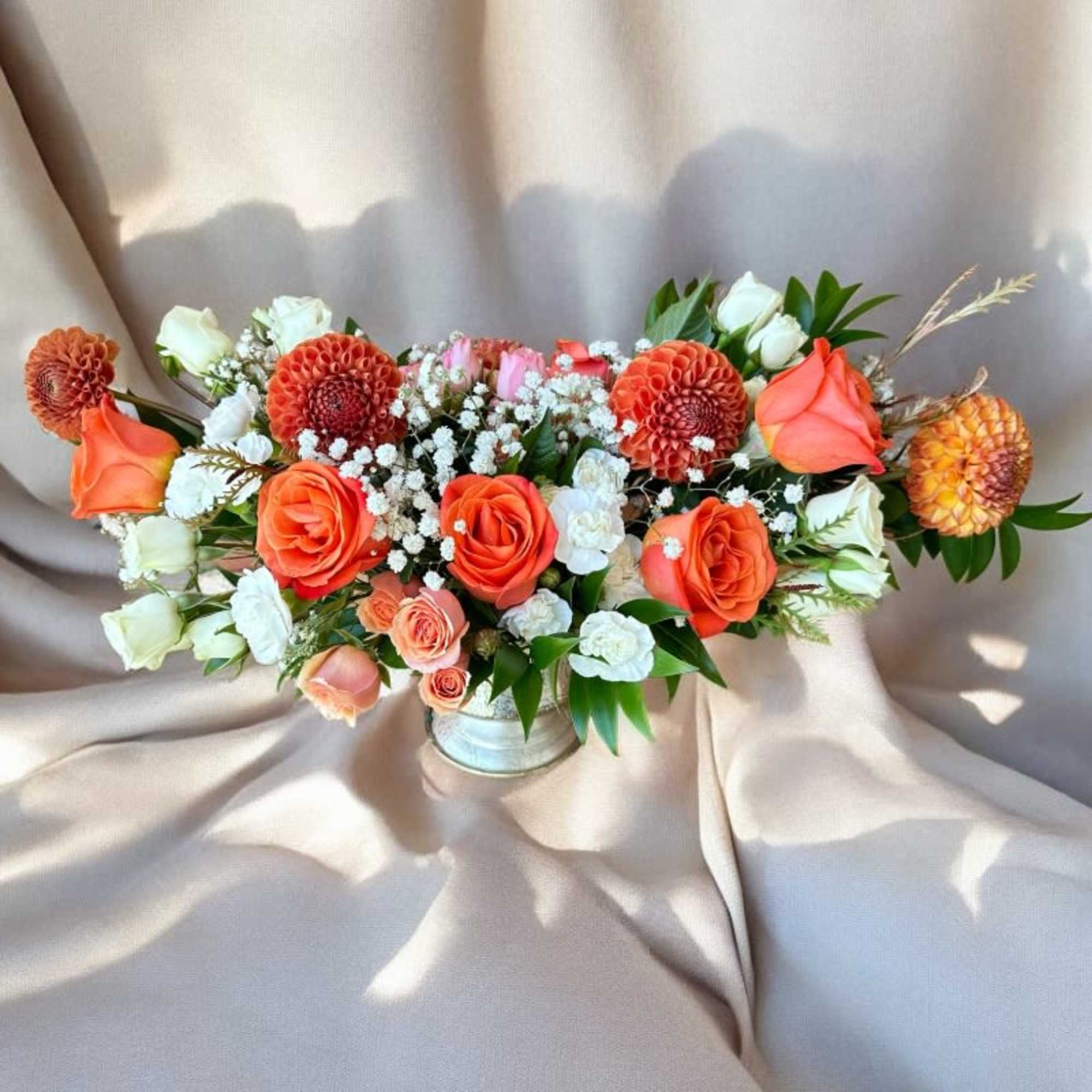 Orange and white floral arrangement in a low vase