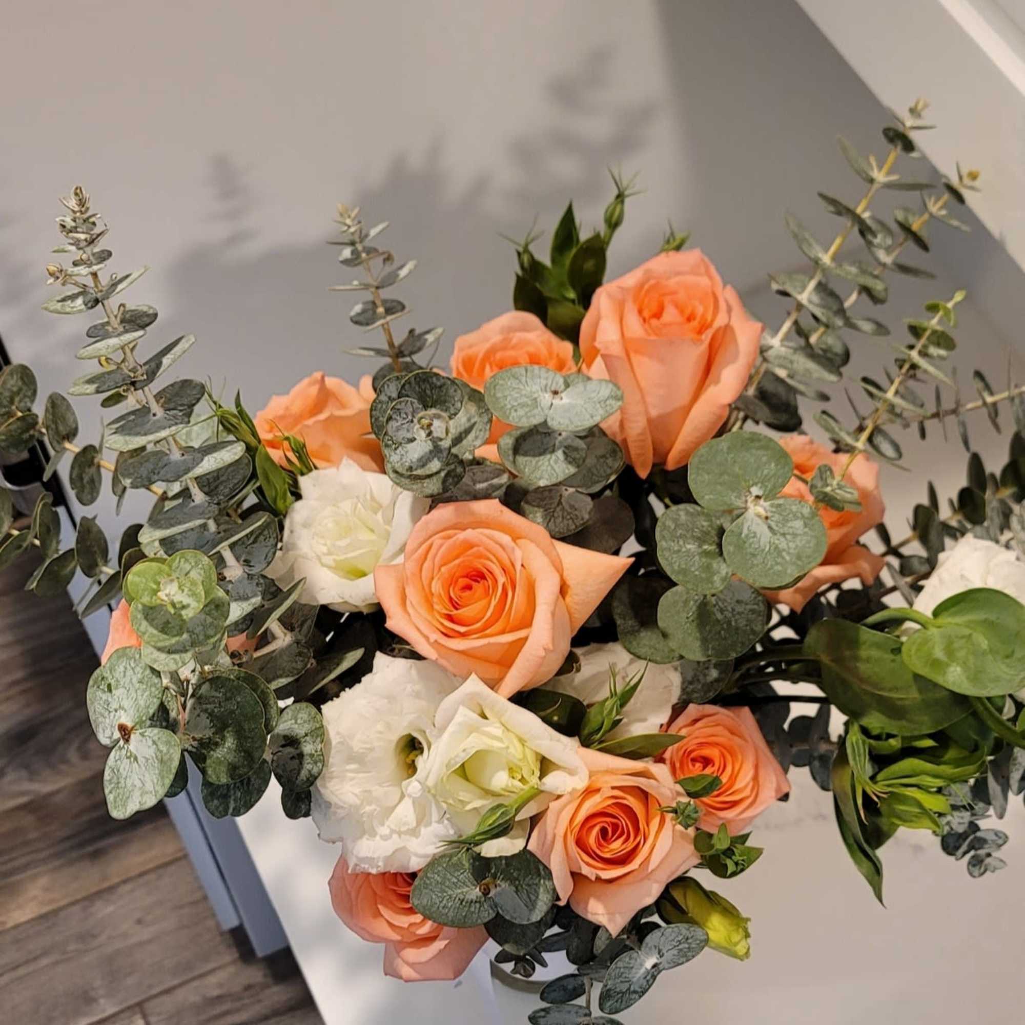Bouquet of peach and white roses with eucalyptus in a vase