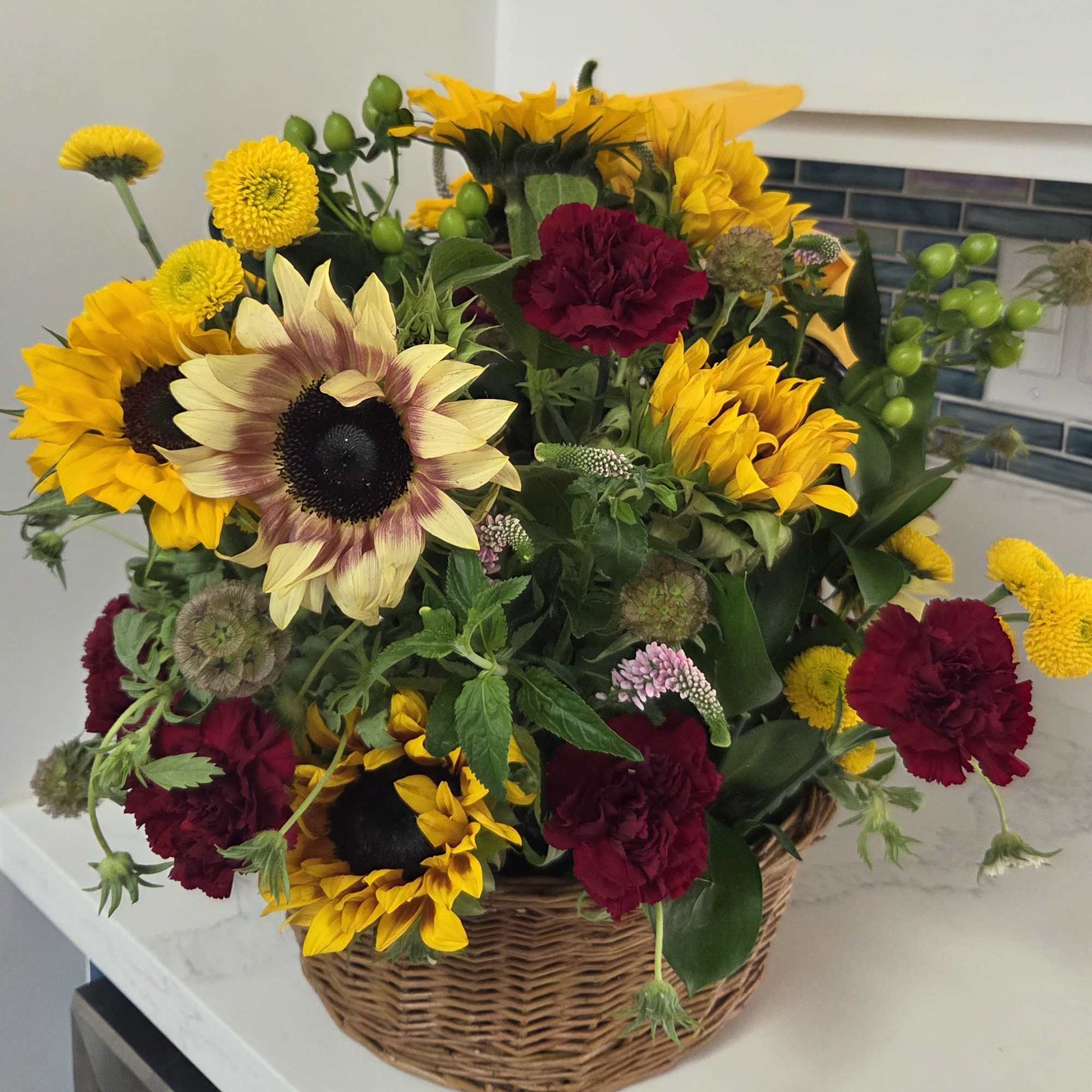 Basket arrangement of sunflowers and burgundy carnations