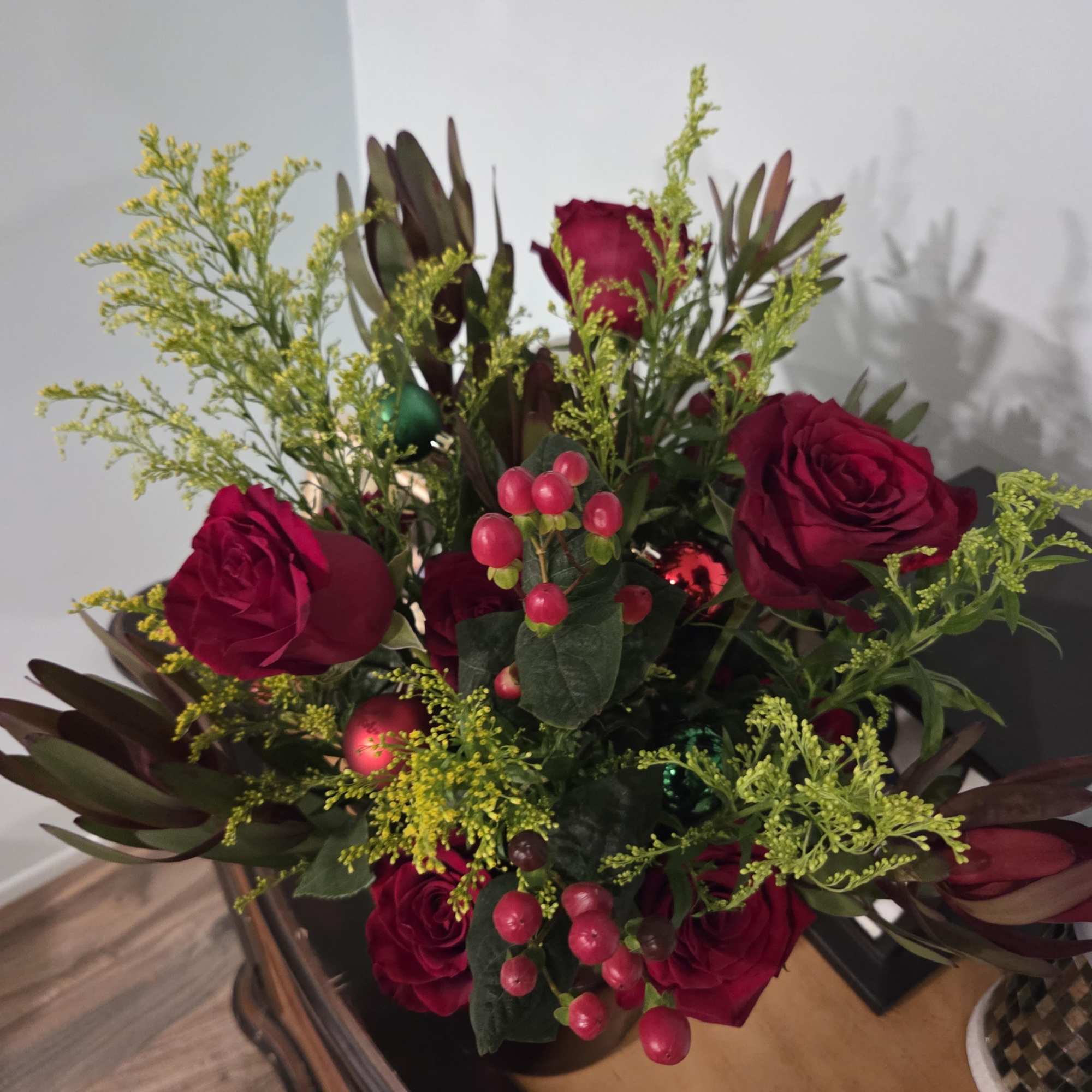 Bouquet of deep red roses with berry accents and yellow filler flowers