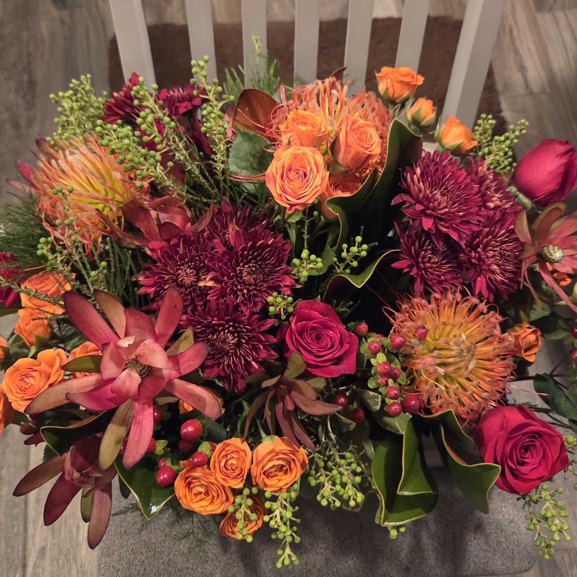 Bouquet of orange and magenta flowers with berries and dark foliage