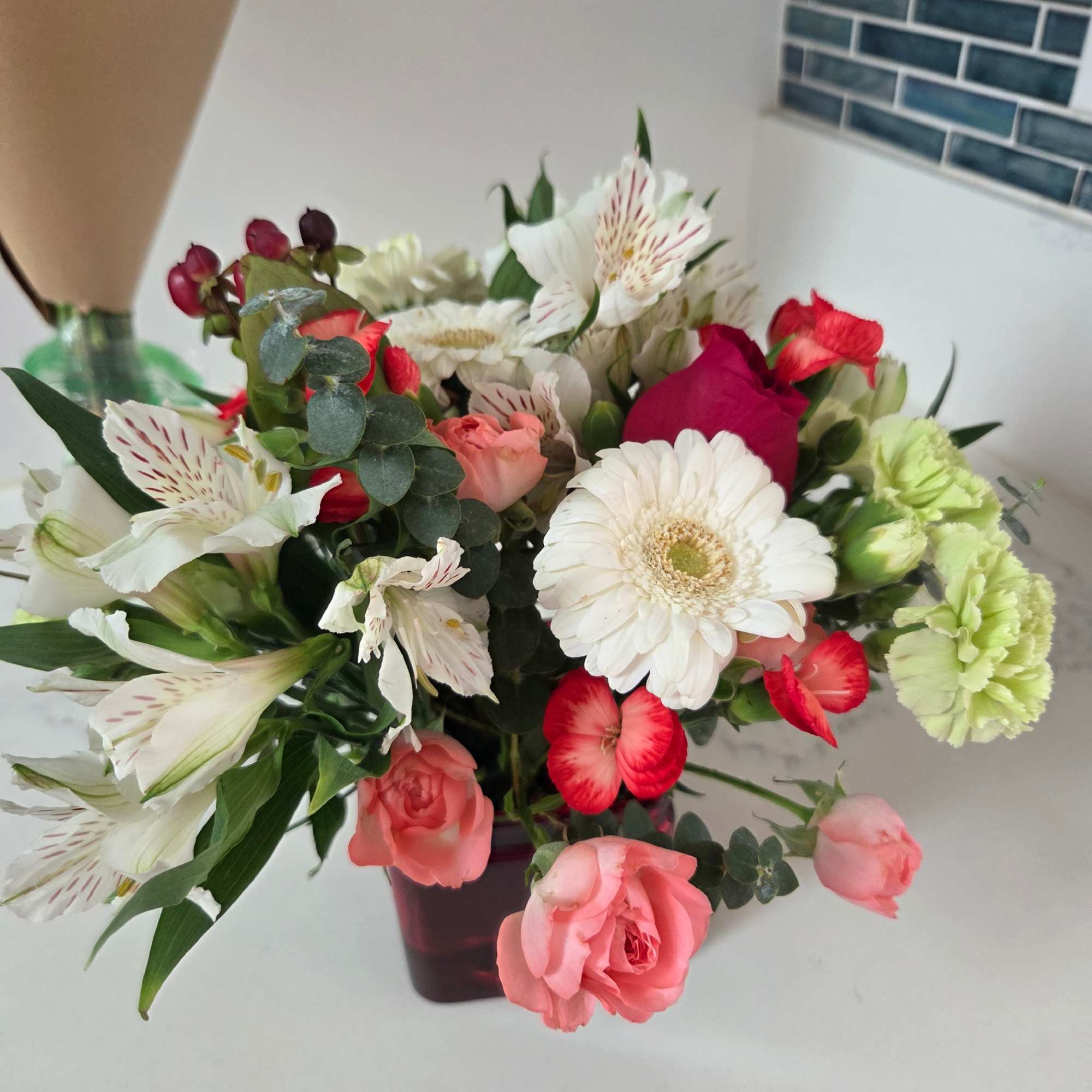 Mixed bouquet of pink, white, and red flowers in a dark vase