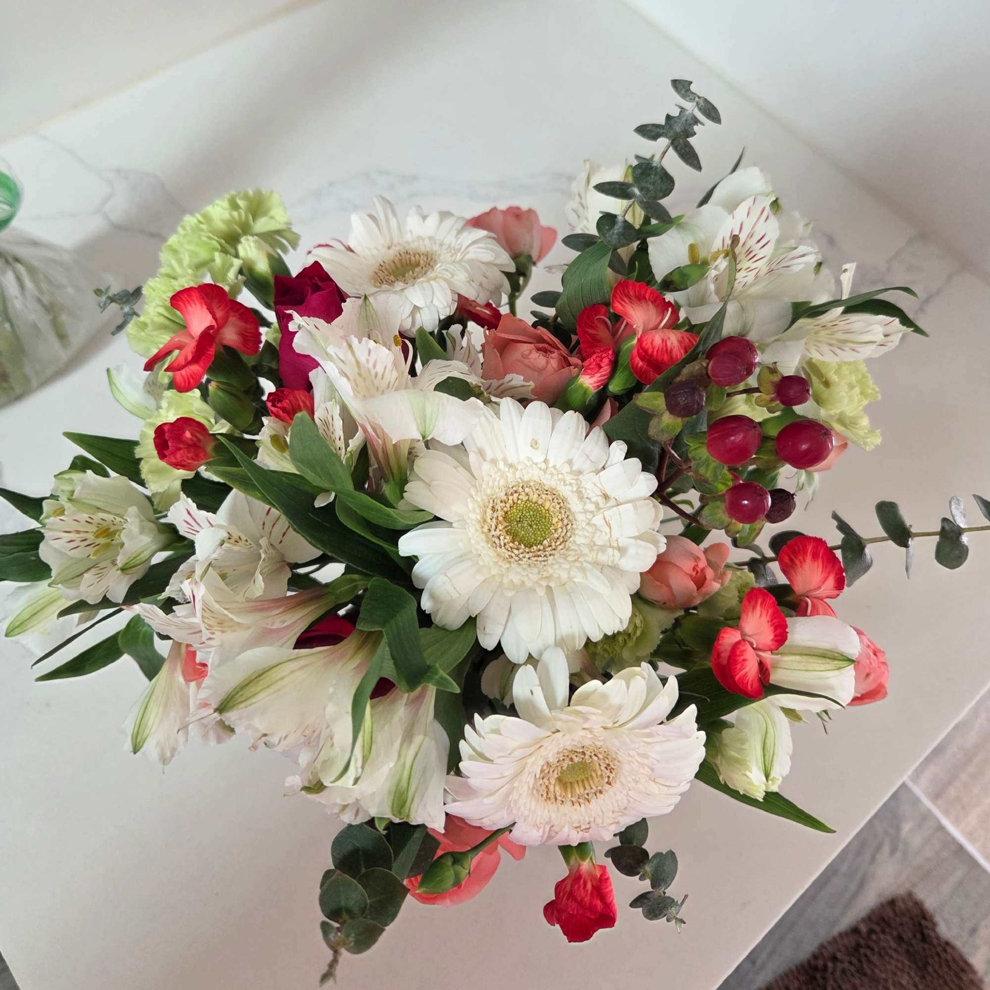 Mixed bouquet with white gerbera daisies, red and pink blooms, and eucalyptus