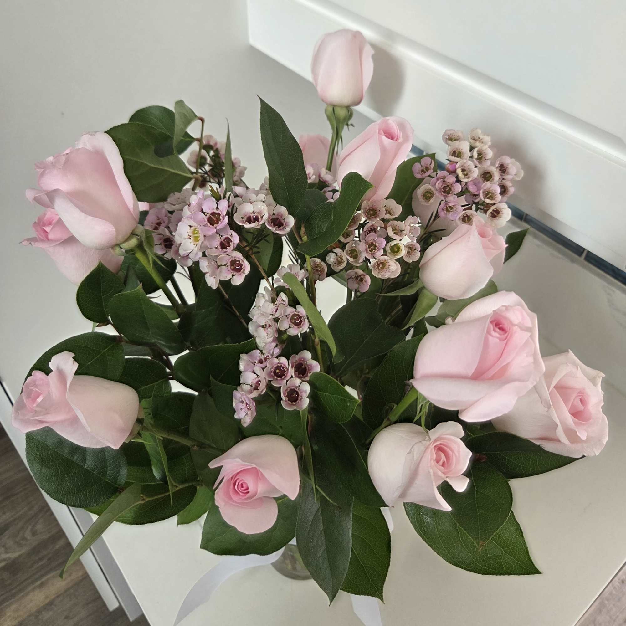 Bouquet of pale pink roses and small pink waxflowers in a glass vase